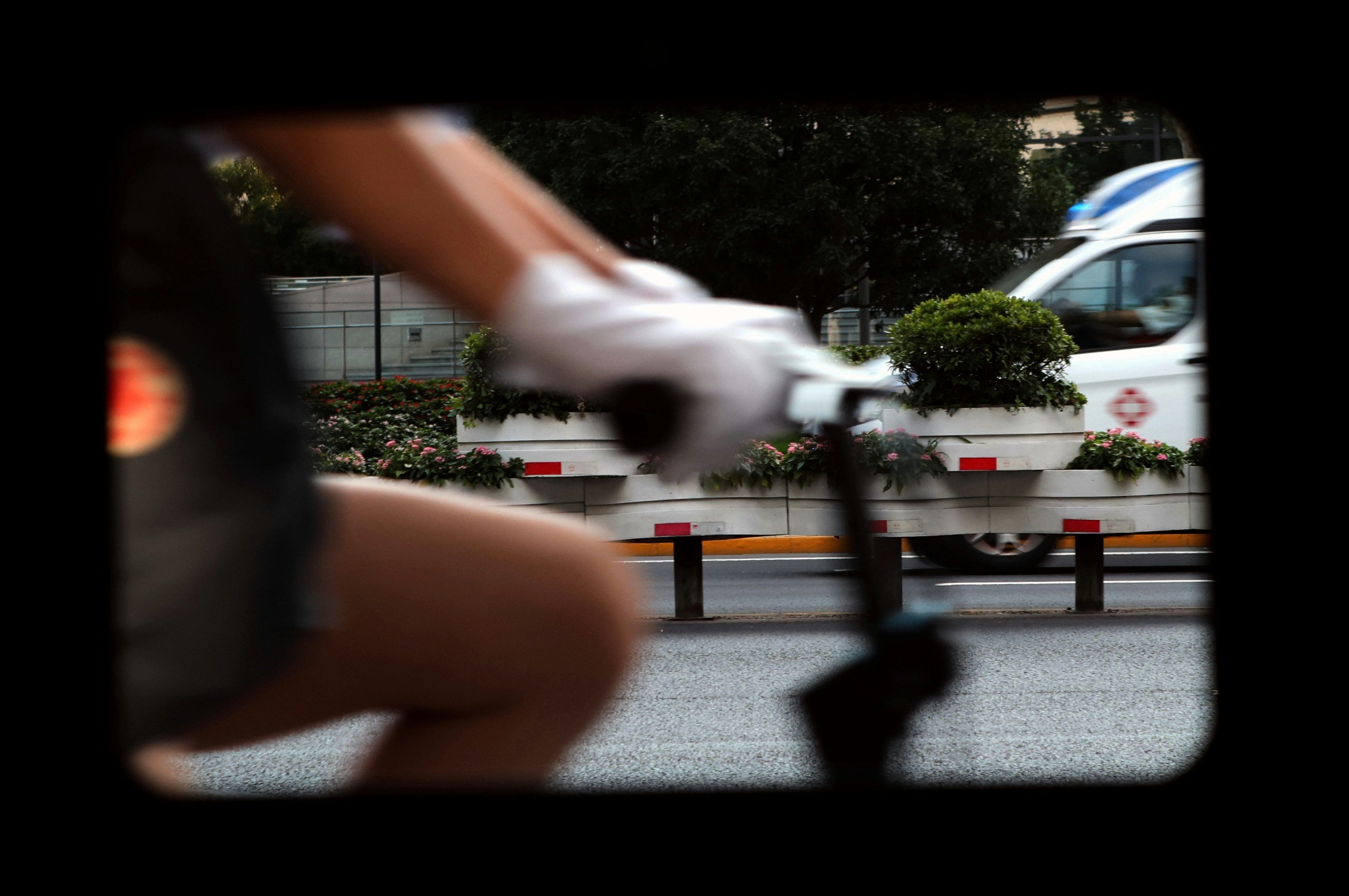 A close-up shot of a police official's gloved hand collecting evidence, blurred in the background to indicate ongoing investigation.