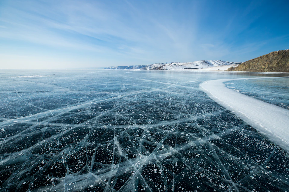 Serene winter landscape with frozen lake at its center surrounded by snow-covered mountains