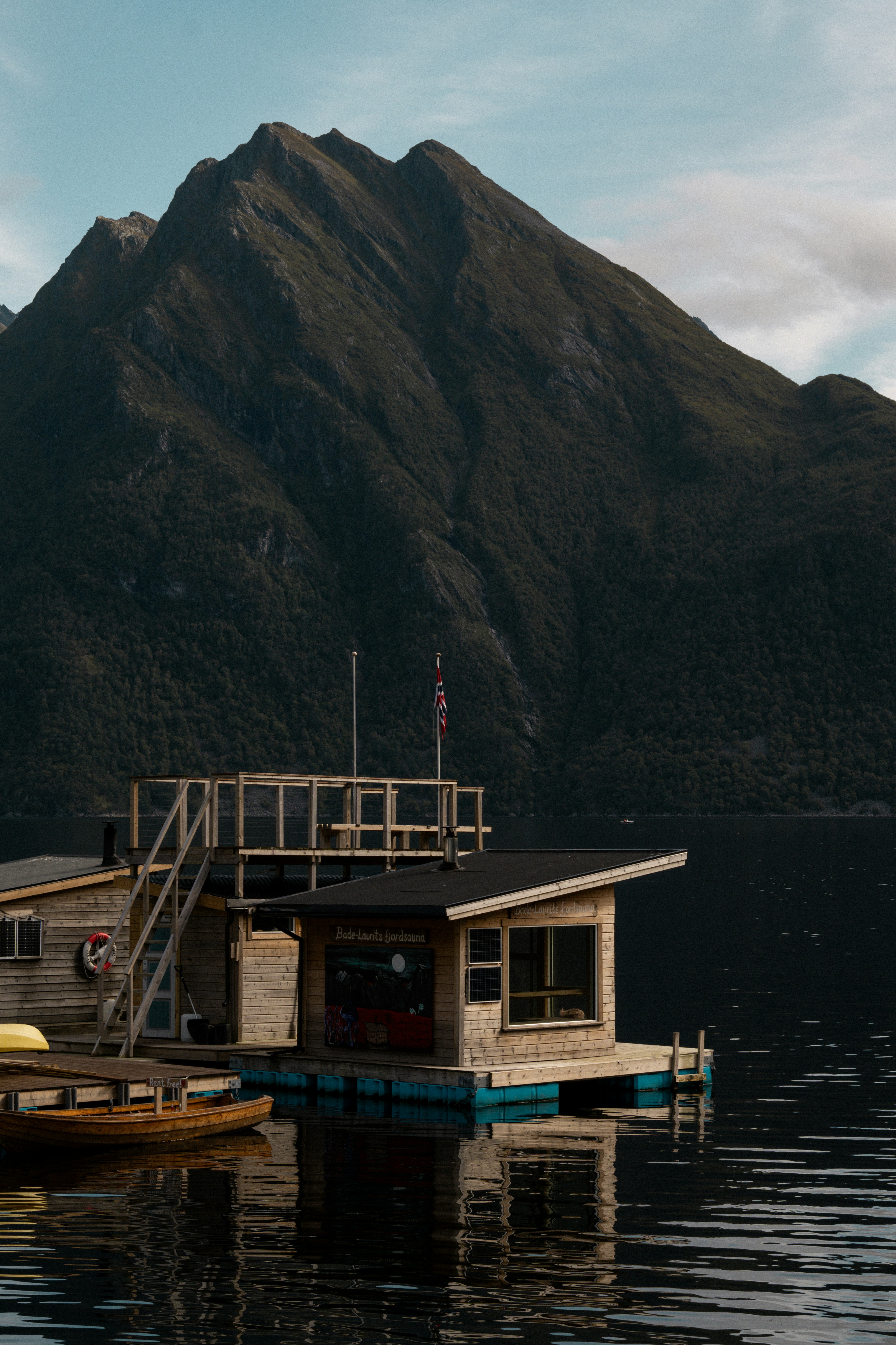 A house boat floating on top of a lake next to a mountain