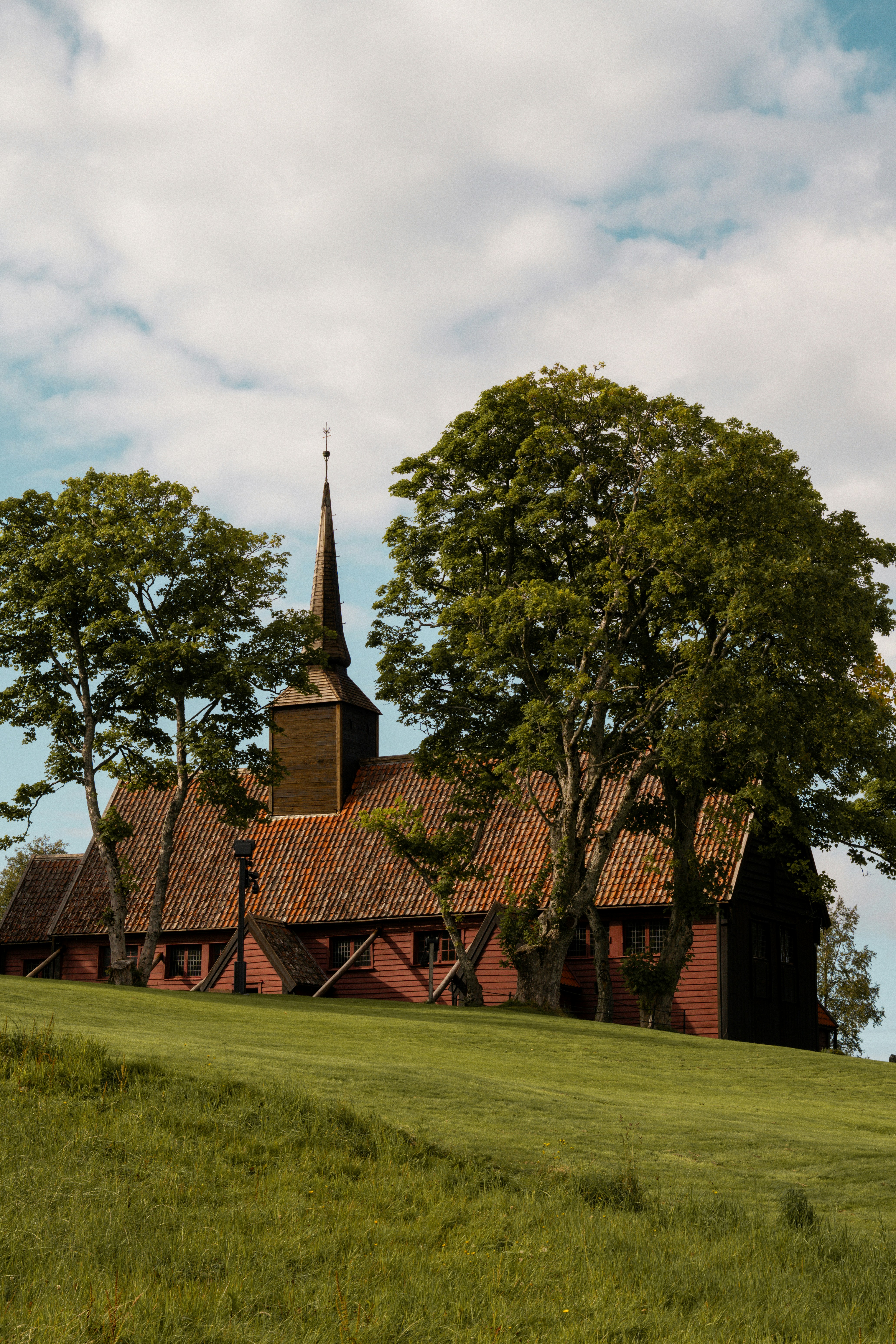 A church with a steeple on a grassy hill