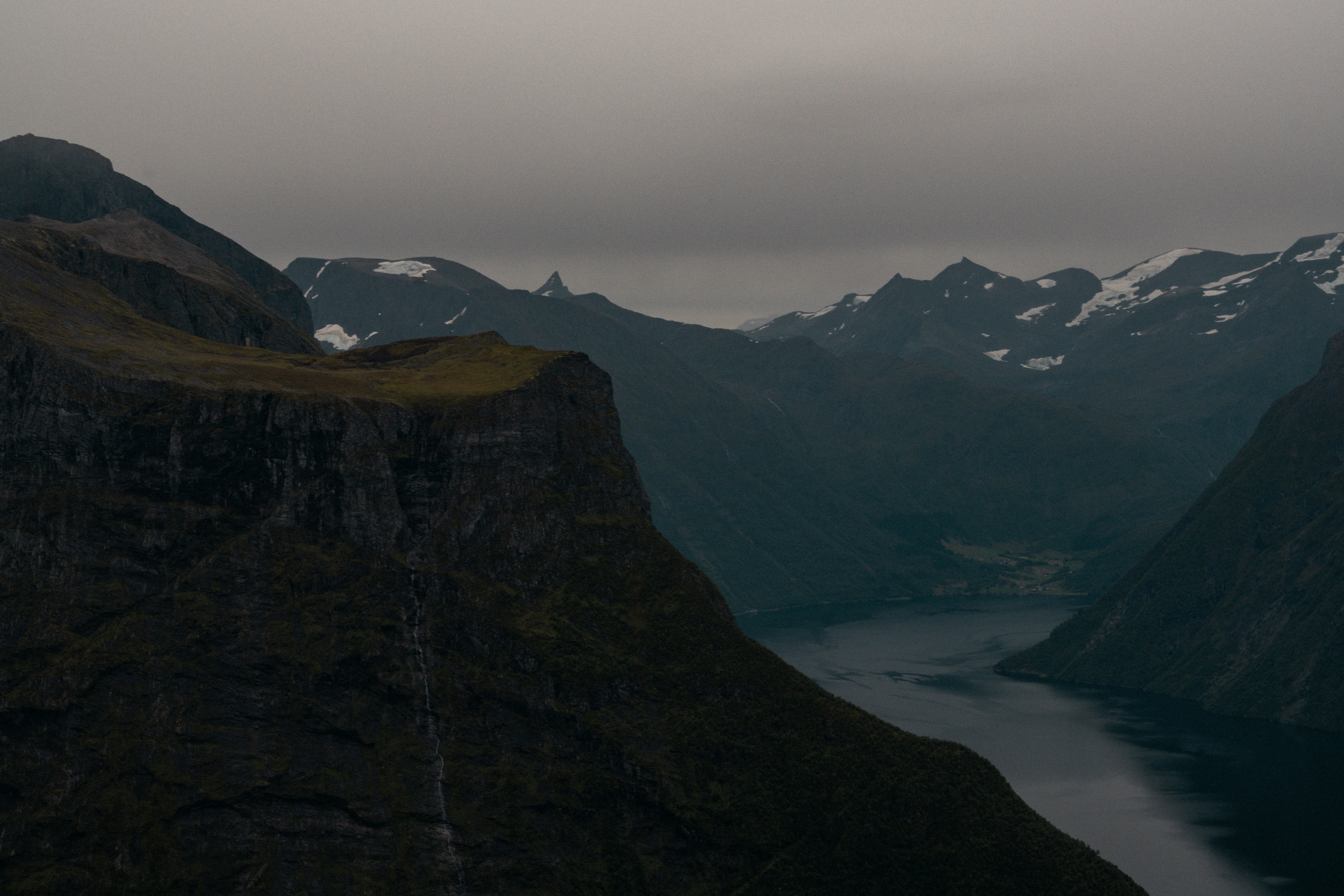 A bird flying over a mountain with a body of water