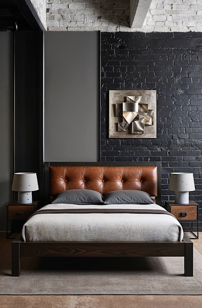 A bed with a brown leather headboard in a bedroom