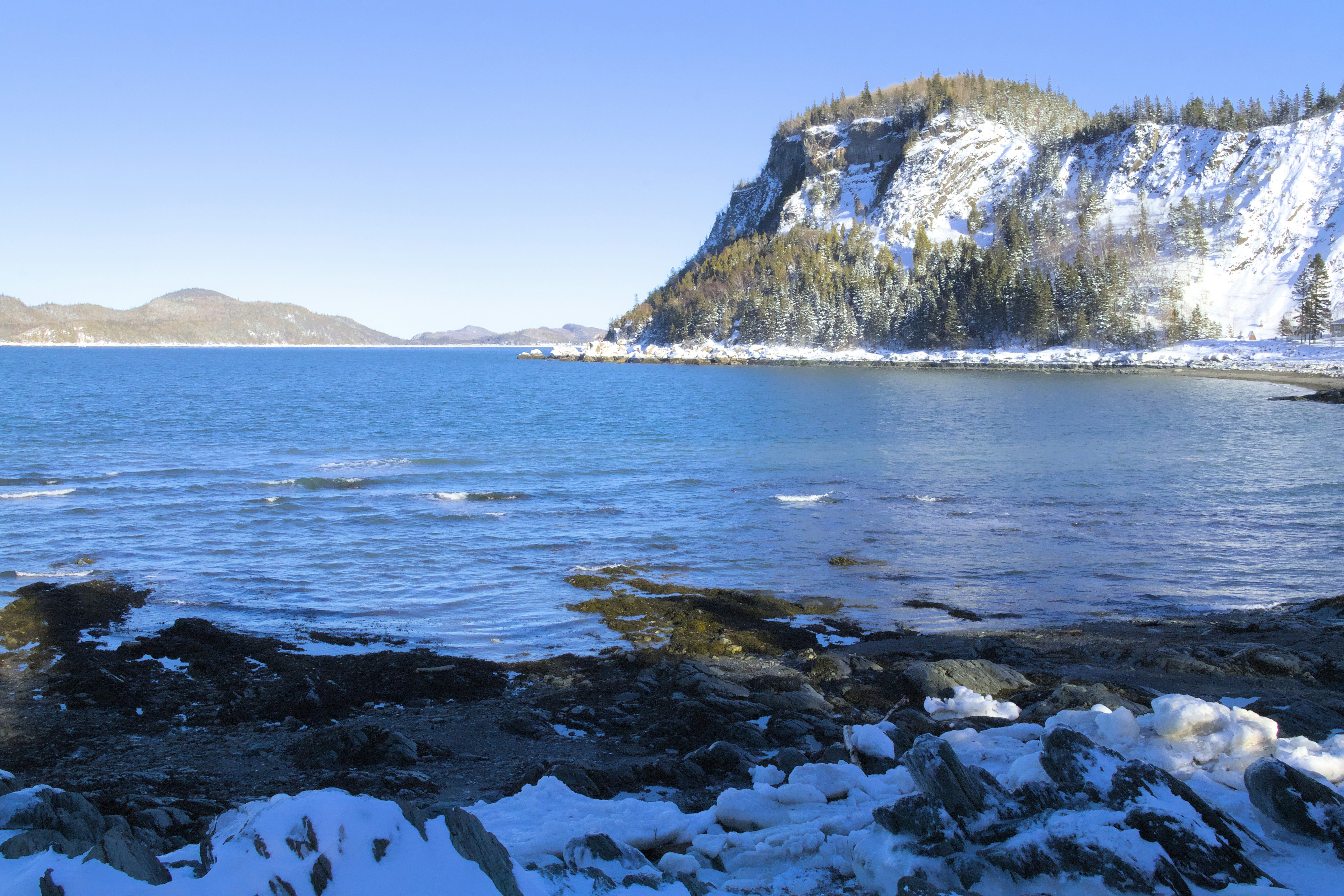 A large body of water surrounded by snow covered mountains