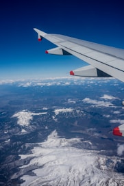 The wing of an airplane flying over a mountain range