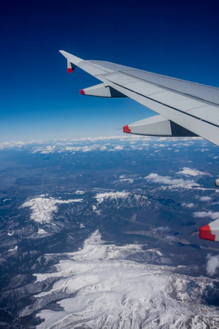 The wing of an airplane flying over a mountain range