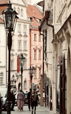 A group of people walking down a street next to tall buildings