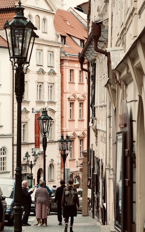 A group of people walking down a street next to tall buildings