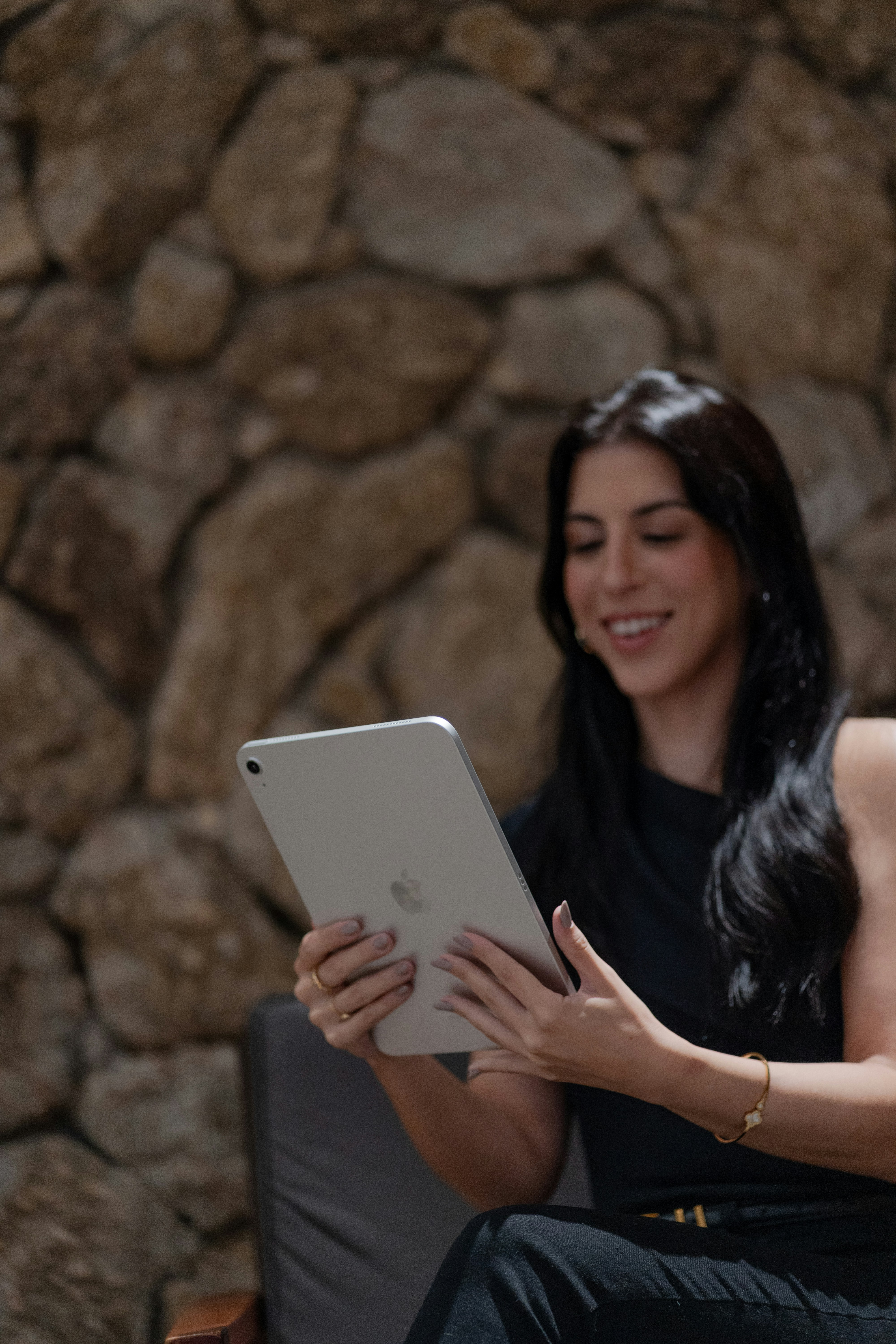Young woman smiling while holding a silver tablet.