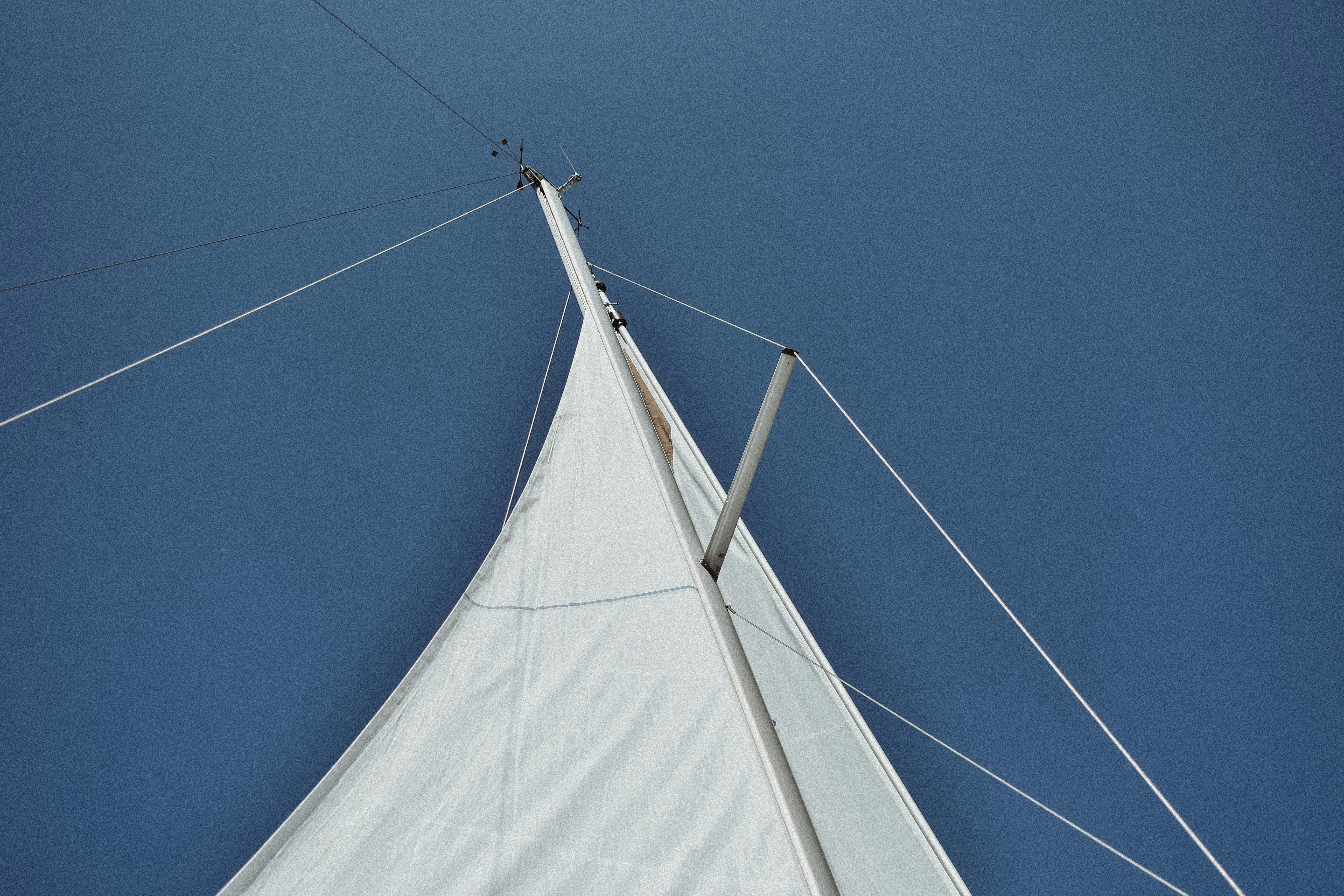 A white sail boat with a blue sky in the background