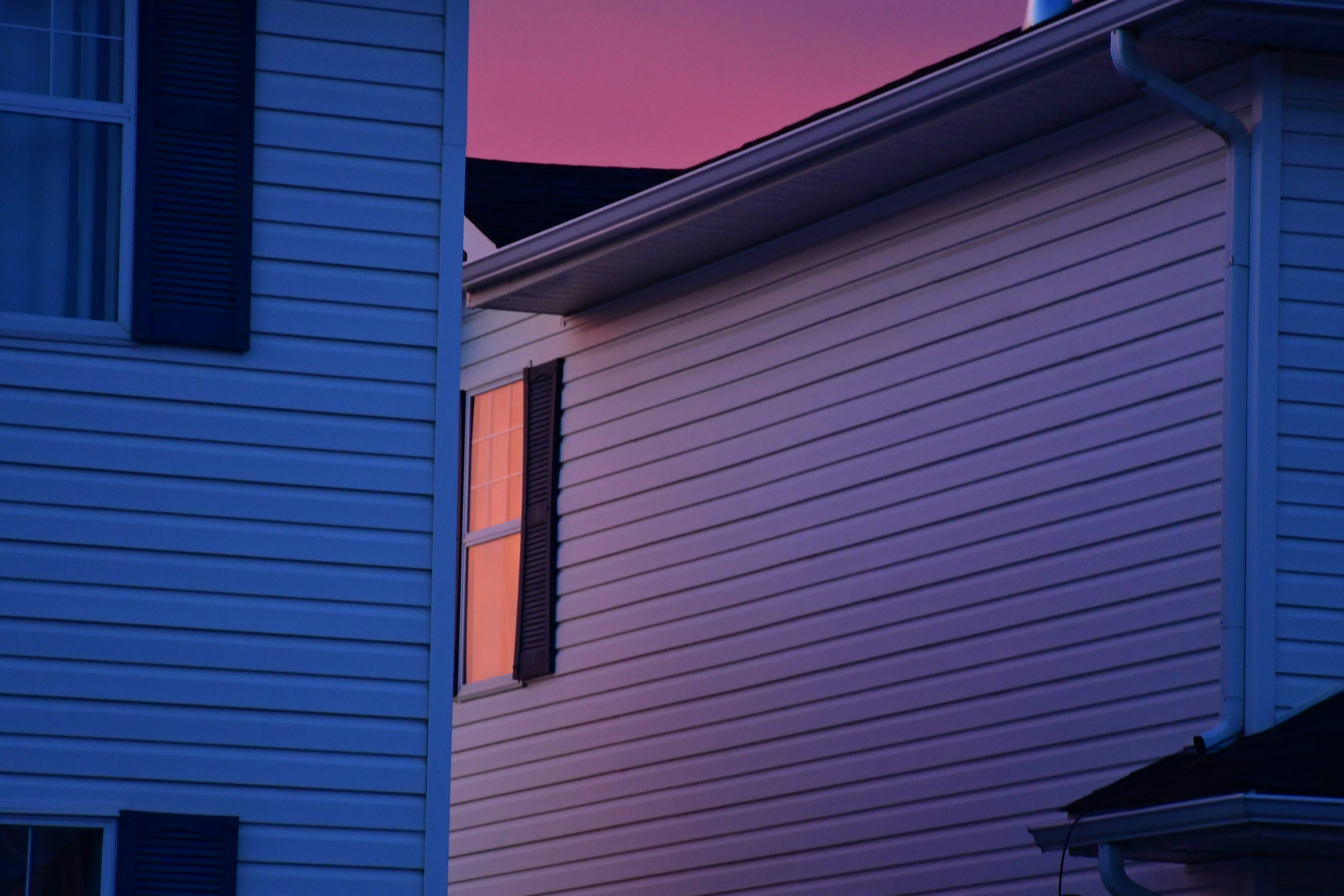A silhouette of a family standing in front of a modern house at dusk, with a subtle glow from inside, symbolizing hope and safety.