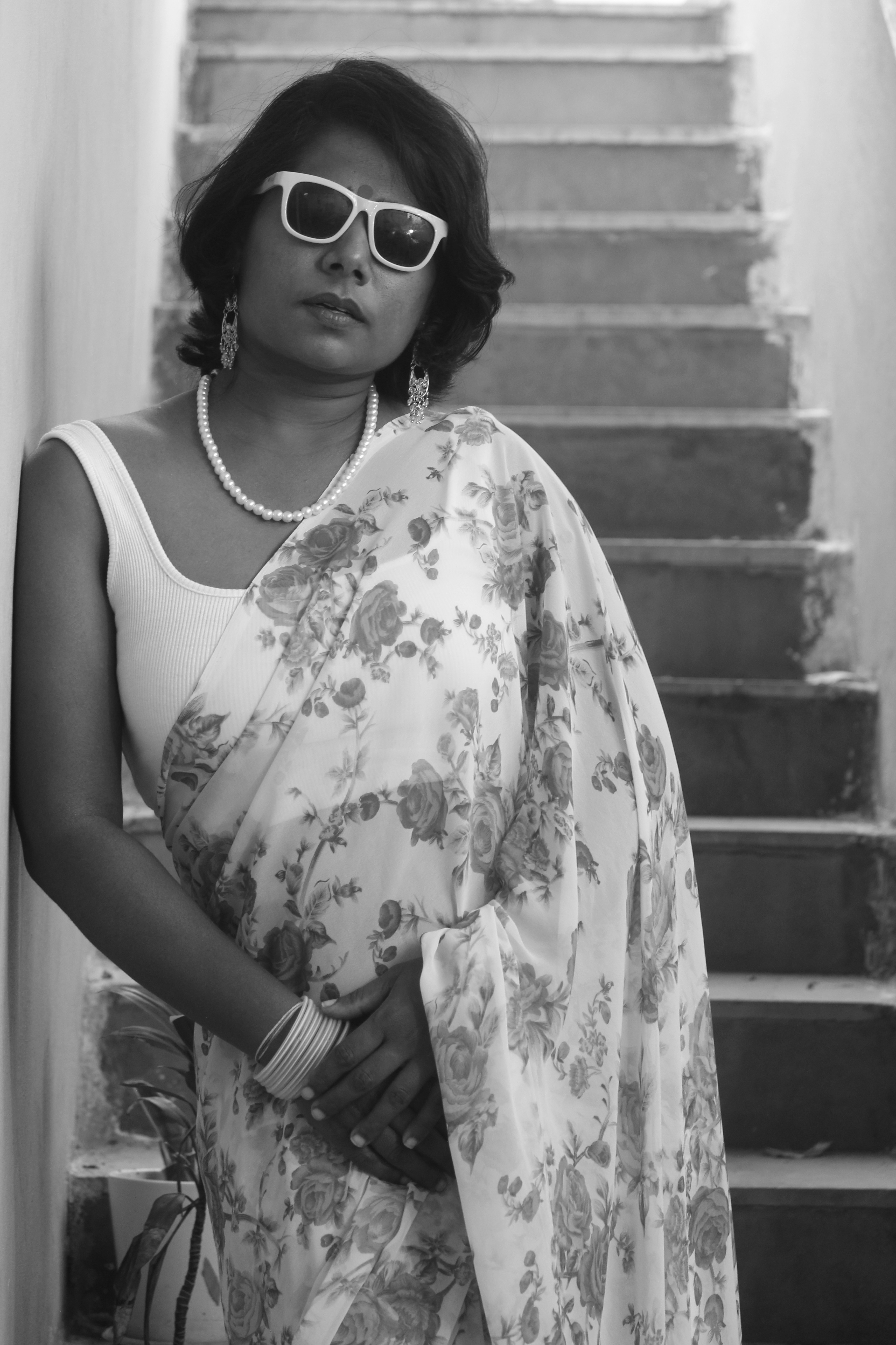 A woman in a sari and sunglasses standing on the stairs