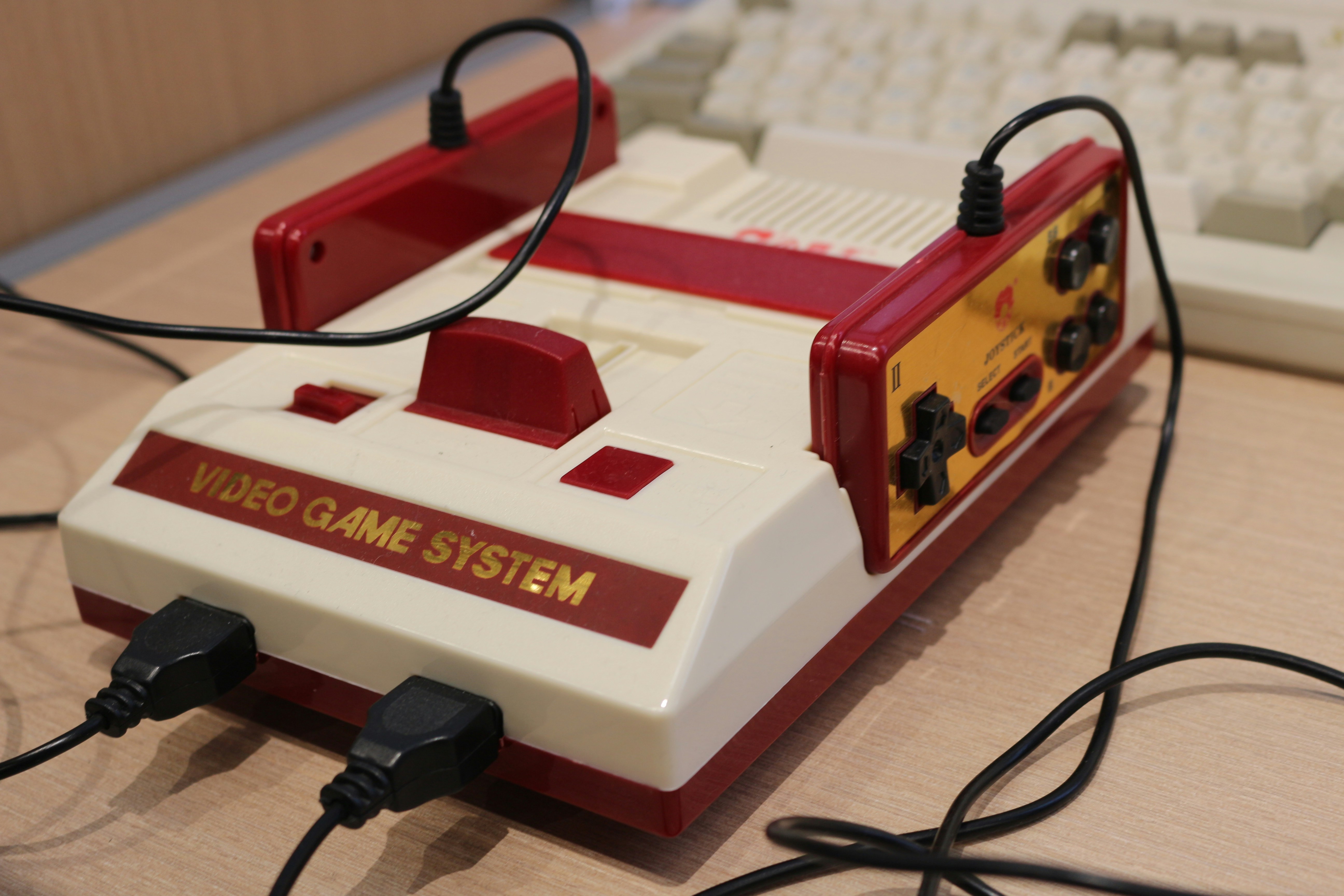 A game system sitting on top of a desk next to a keyboard