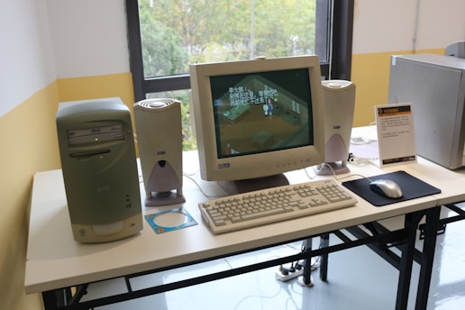 A desk with a monitor, keyboard, mouse and speakers