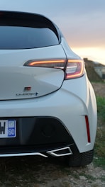 The rear end of a white car parked in a field