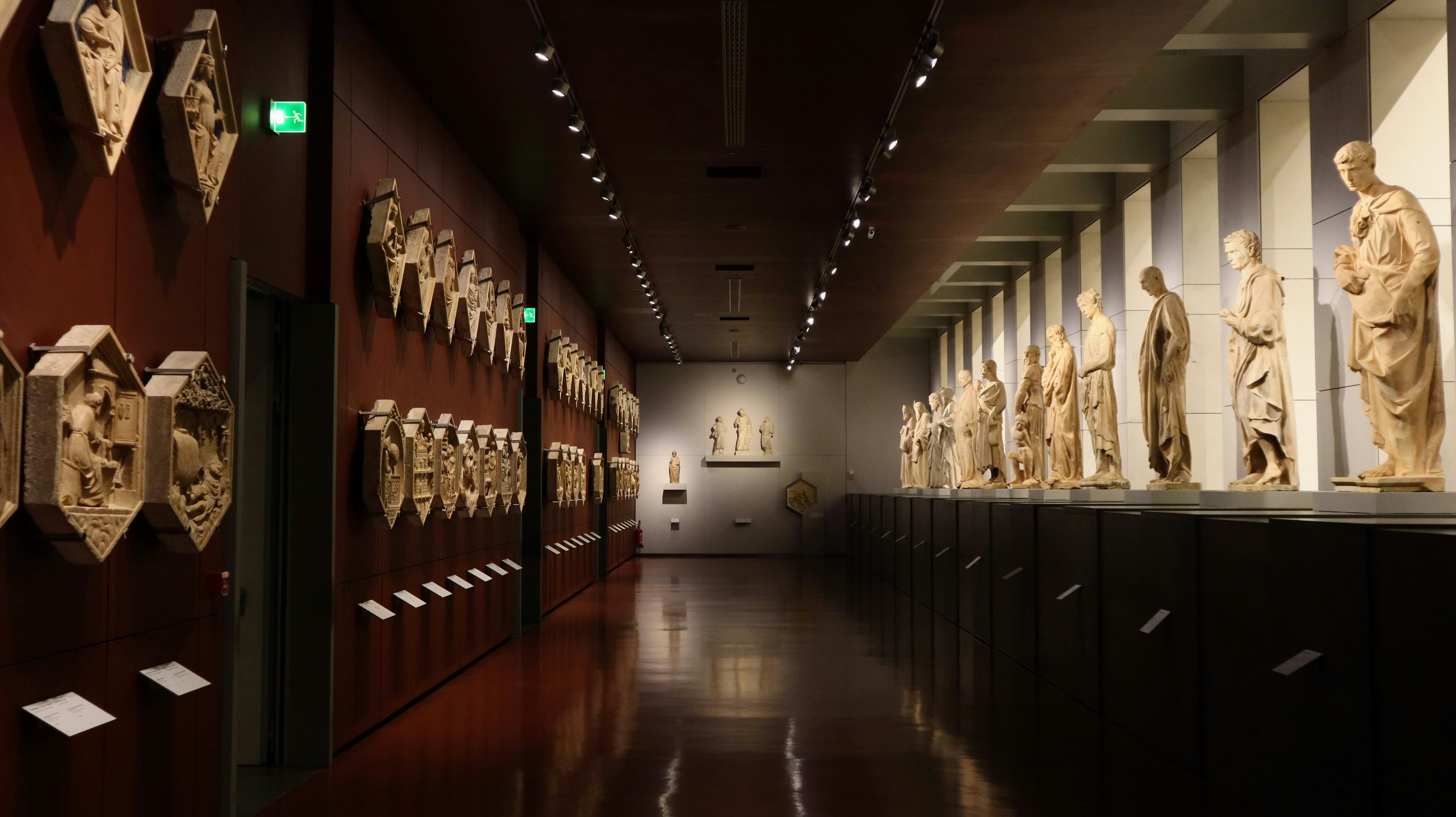 A long hallway with many sculptures on the wall