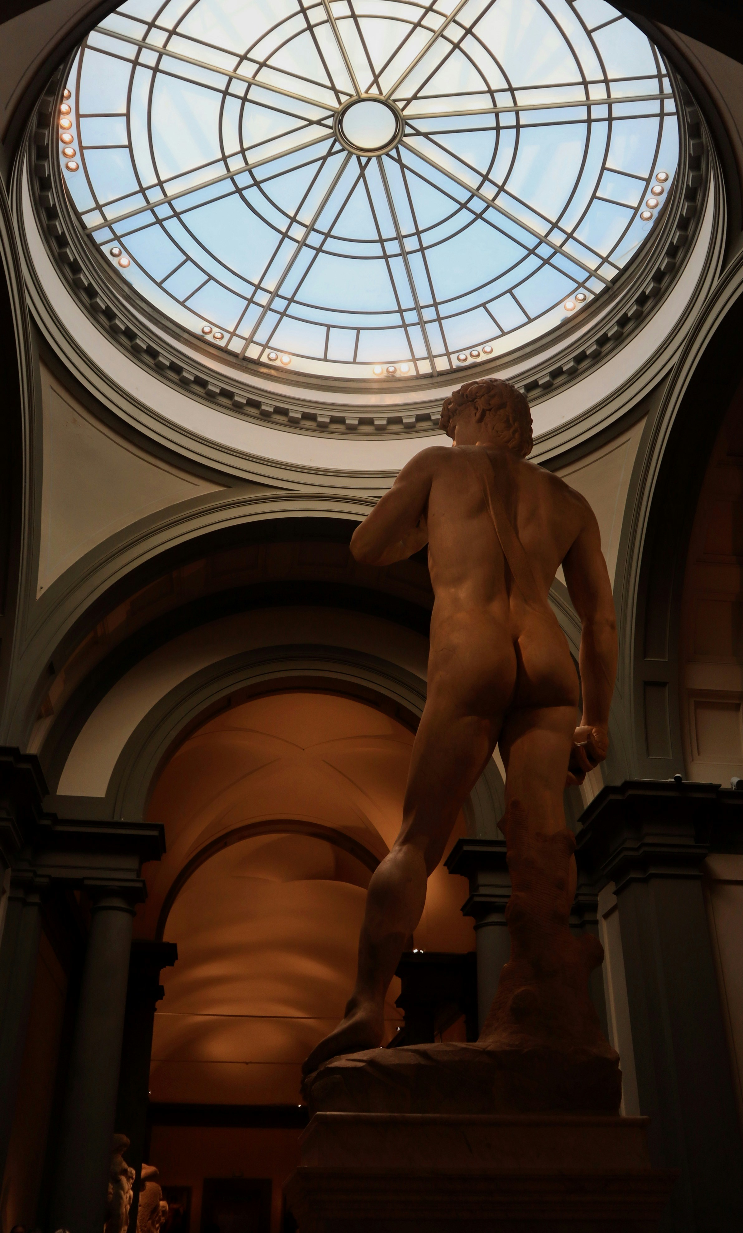 A statue of a naked man in front of a round window
