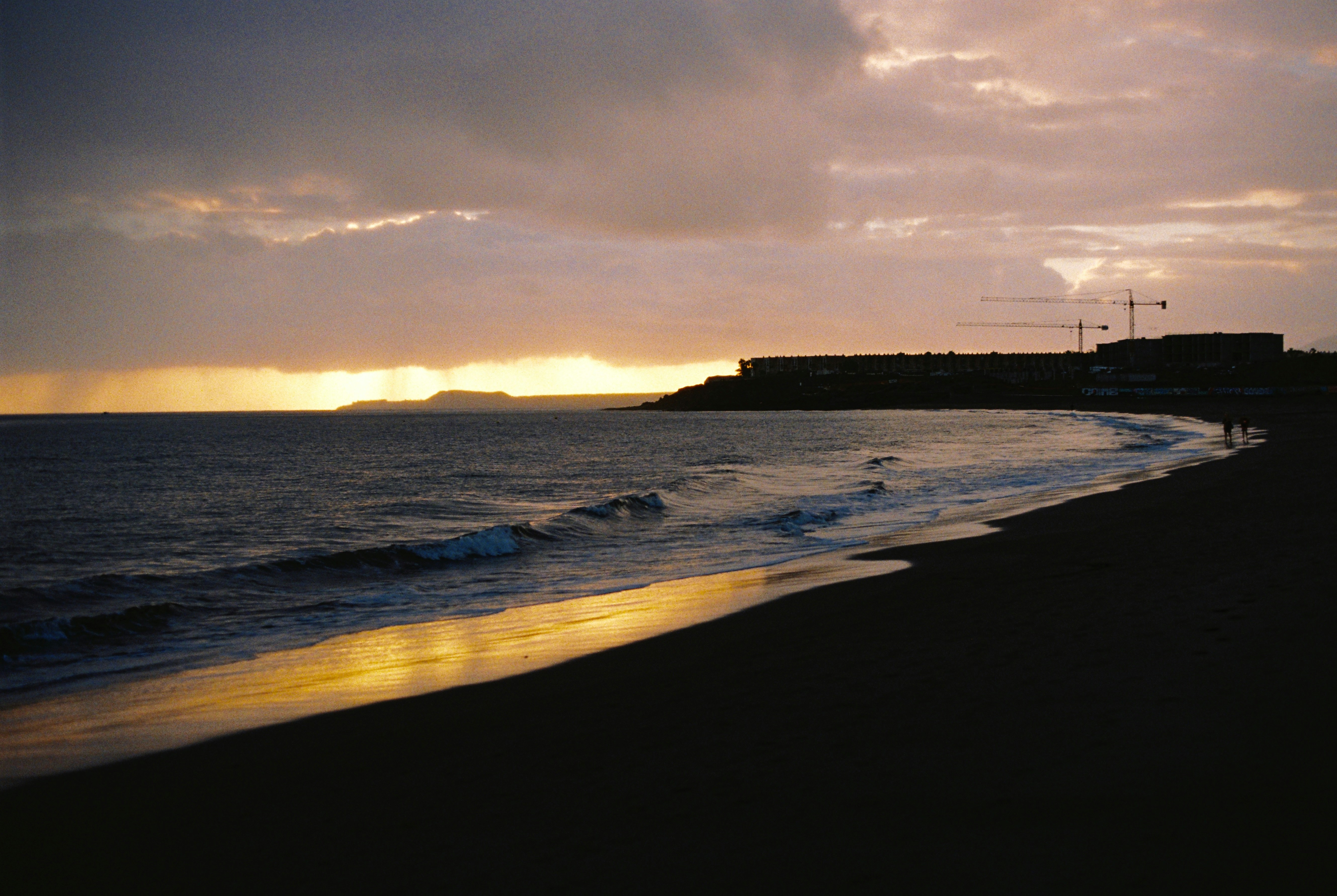 The sun is setting over the ocean and a beach, 