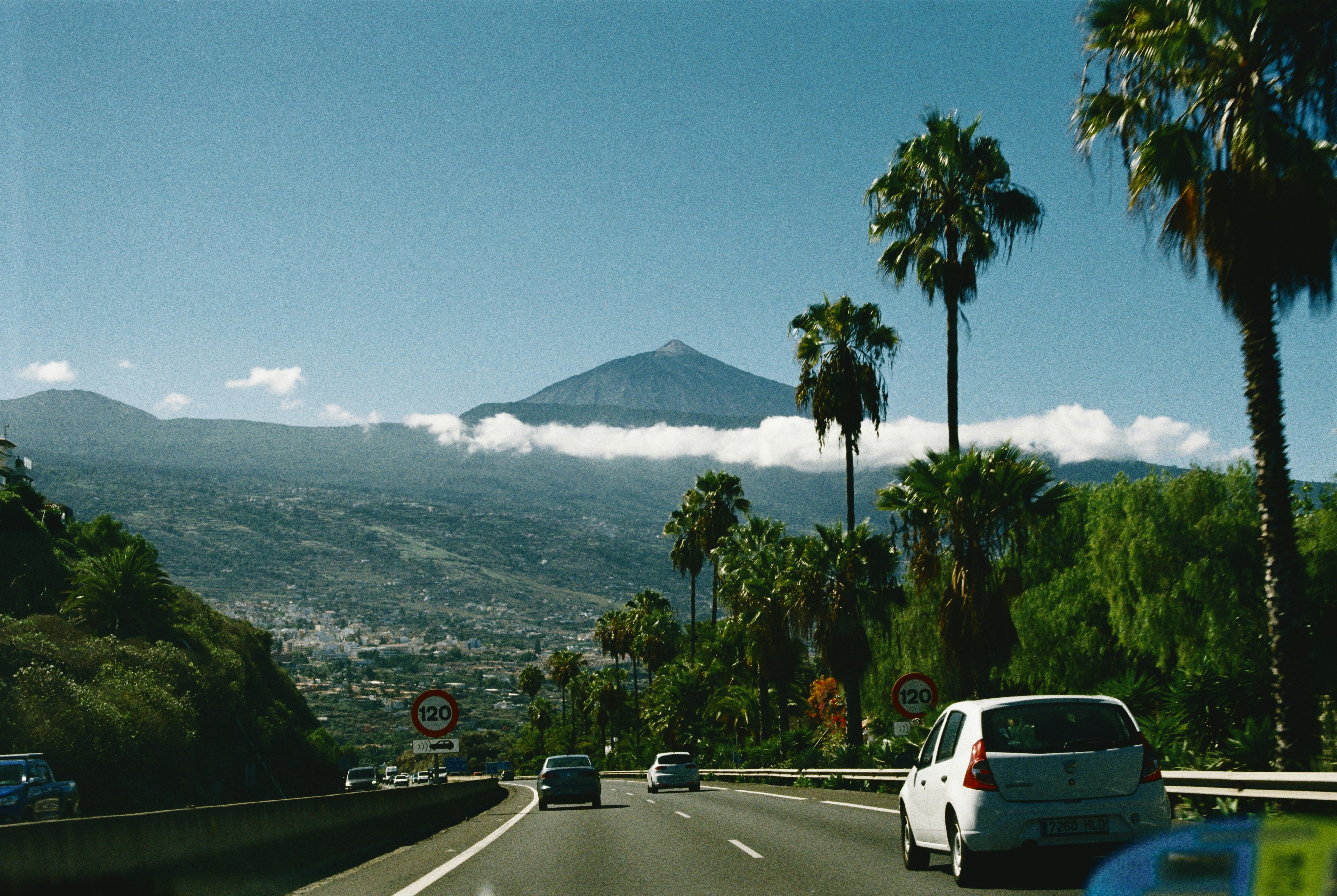 A car driving down a road with a mountain in the background