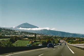 A car driving down a road with a mountain in the background