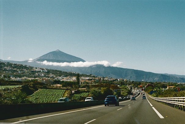 A car driving down a road with a mountain in the background