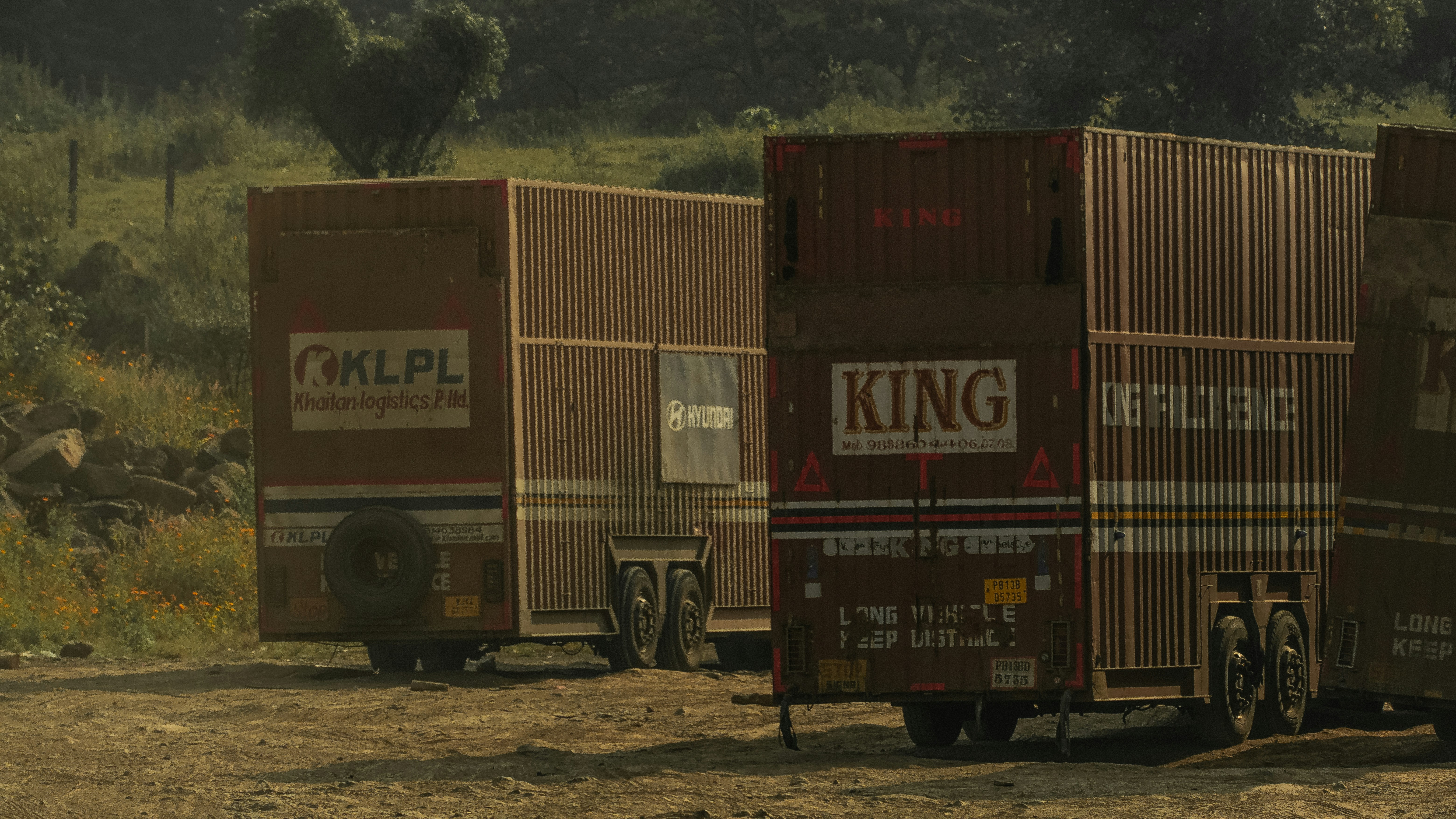 A group of cargo trucks parked on a dirt road