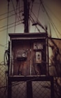 An old telephone box sitting on top of a fence