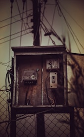 An old telephone box sitting on top of a fence