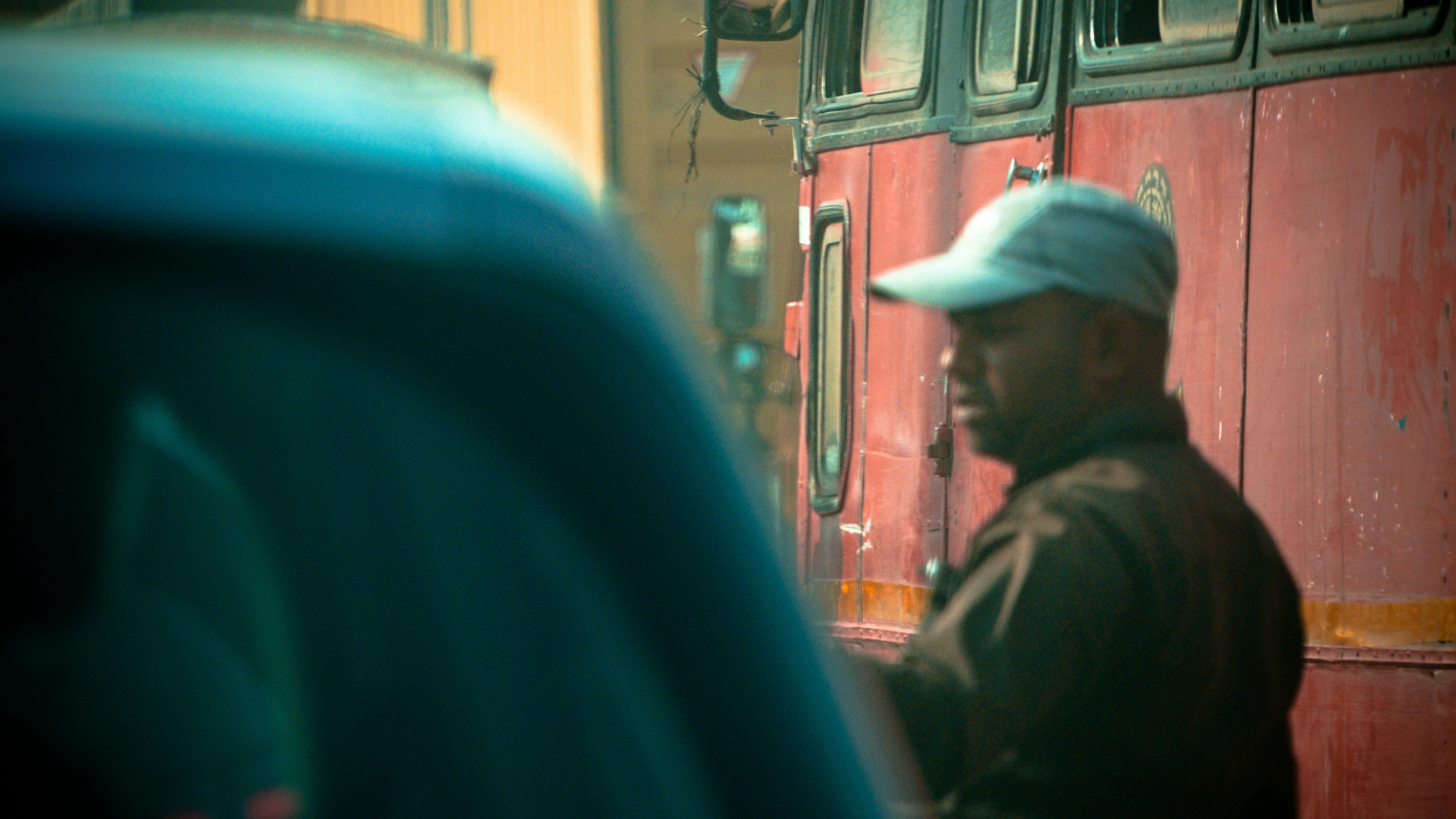 A man standing in front of a red bus