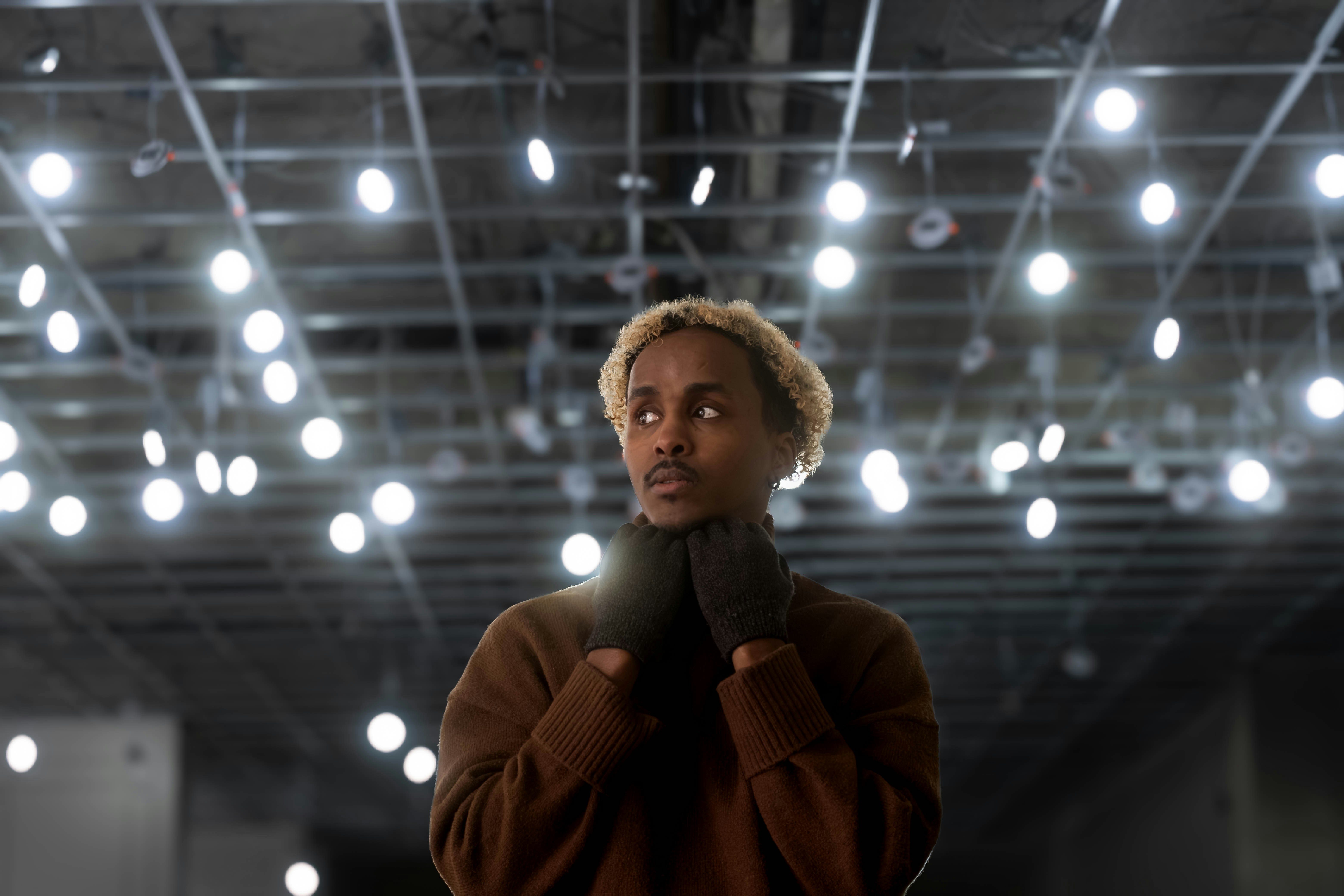 A woman standing in a room with lights on the ceiling