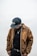 A man wearing a brown jacket and black hat
