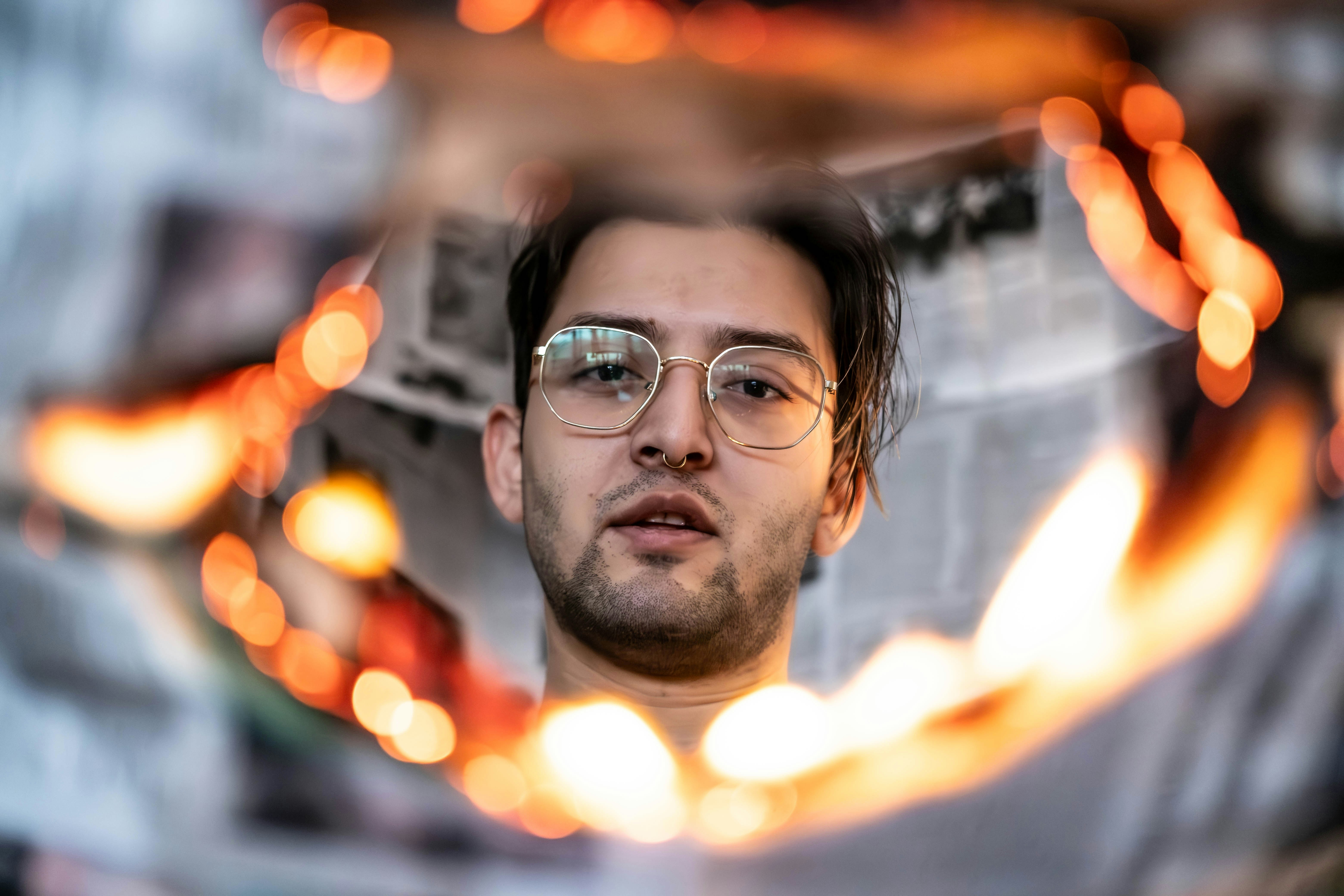 A man with glasses is looking in a mirror