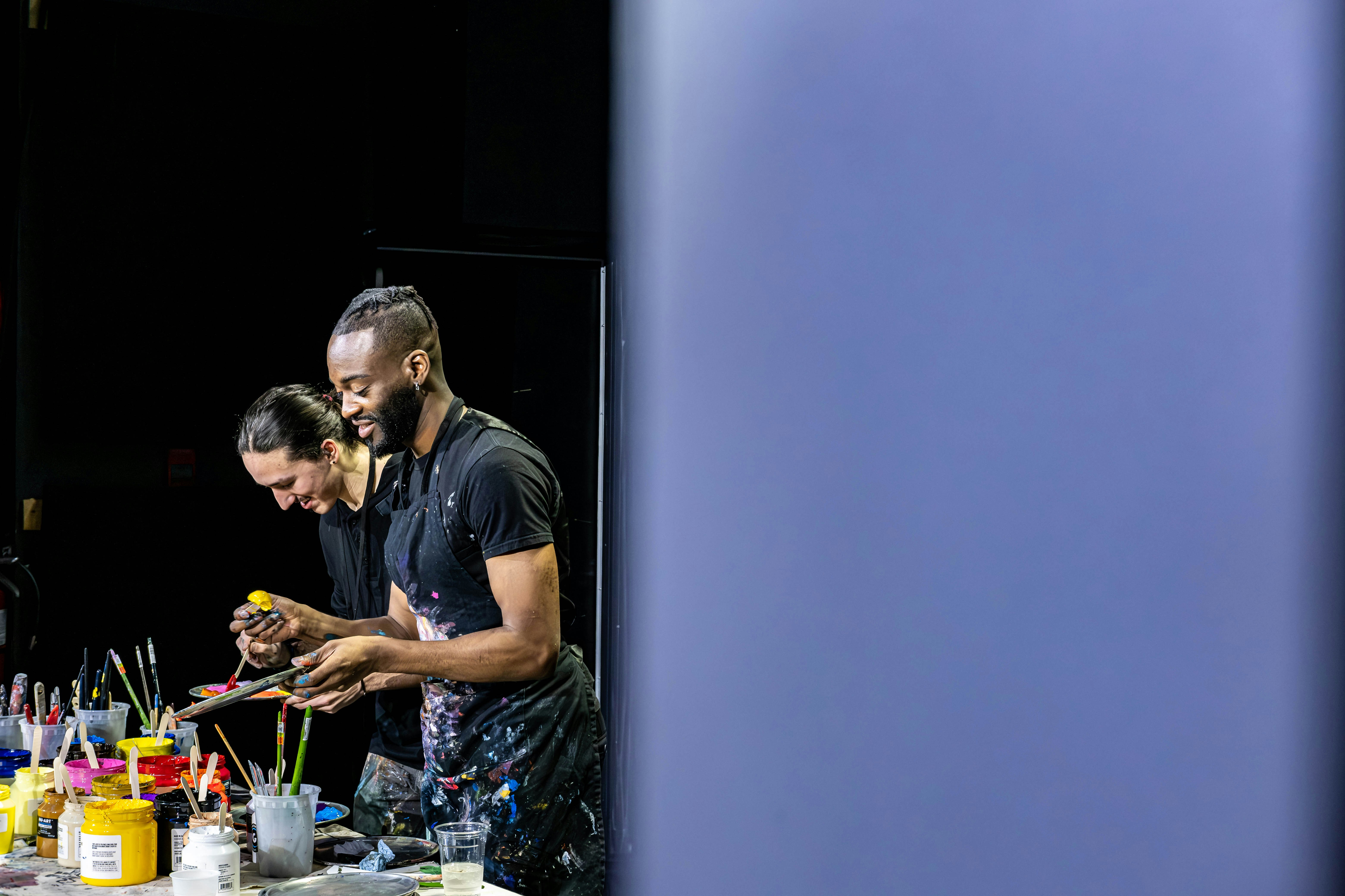 A group of men standing around a table filled with paint
