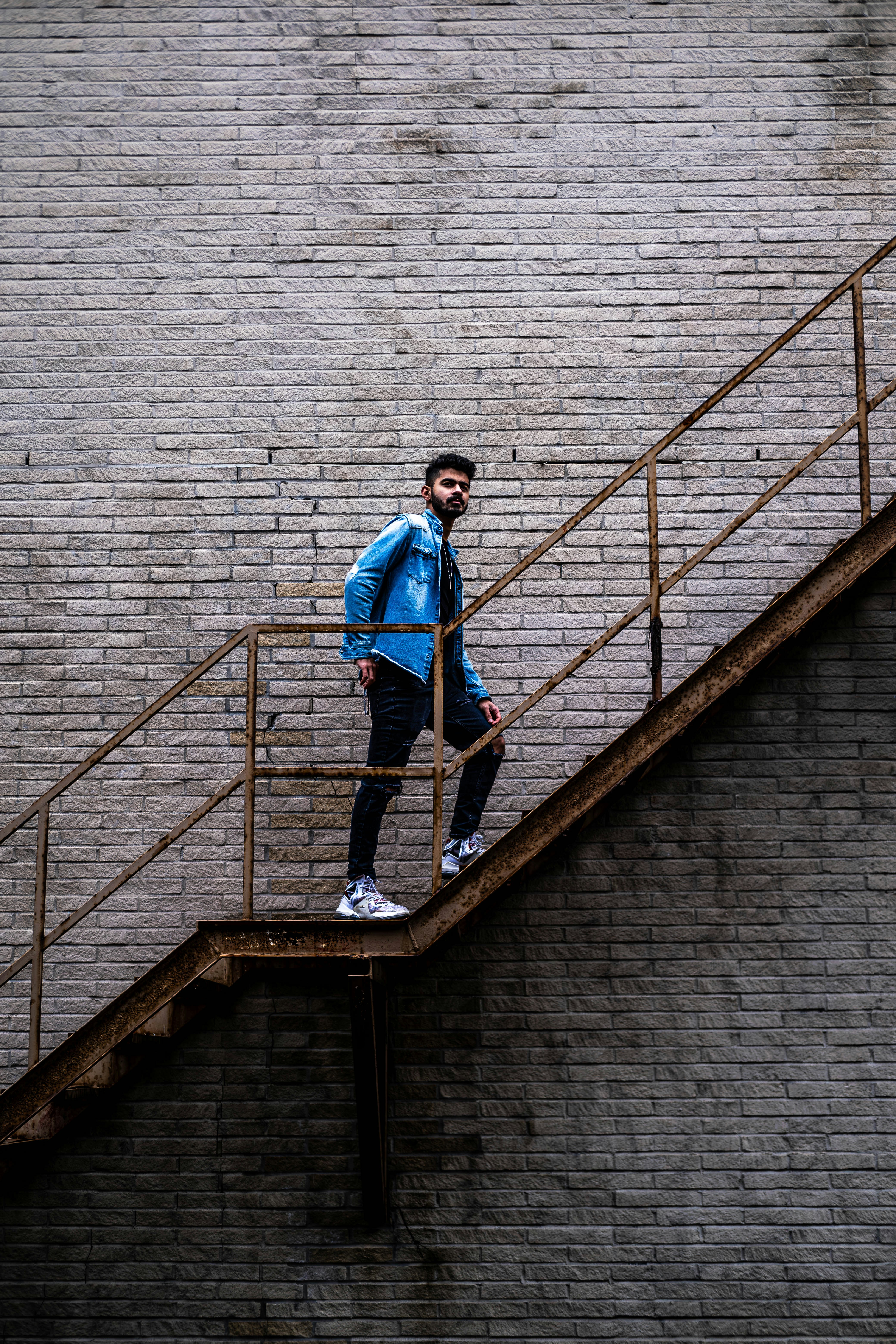 Ein Mann steht auf einem Treppengeländer neben einer Backsteinmauer