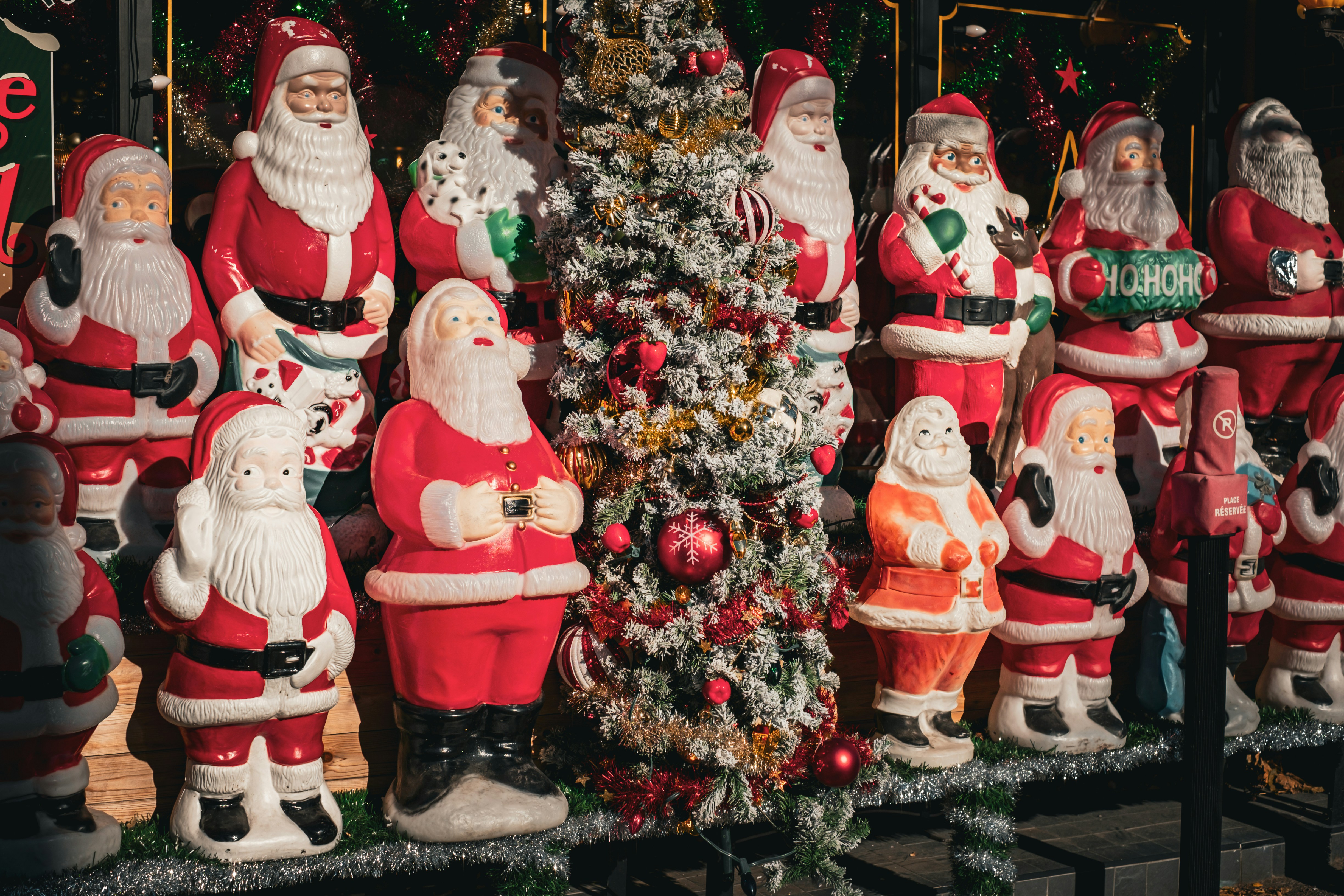 A group of santa clause figurines next to a christmas tree