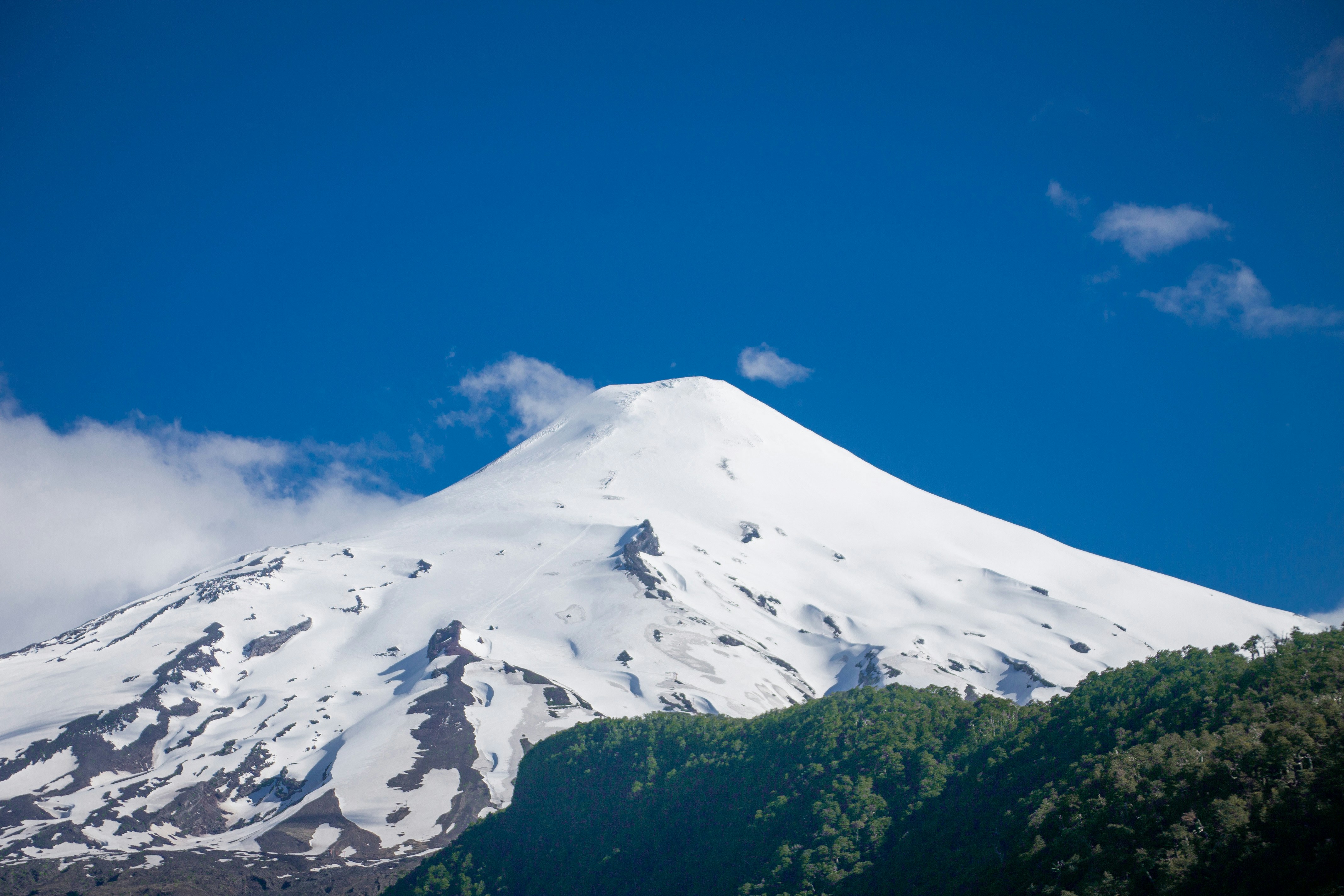A large snow covered mountain with a blue sky in the background