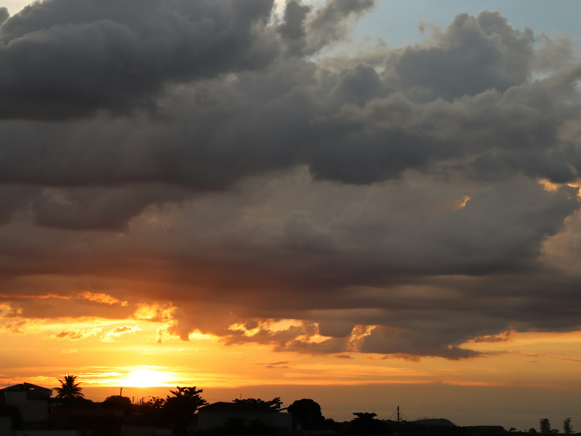 The sun is setting behind a cloudy sky