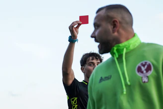 A man in a green hoodie holding up a red card