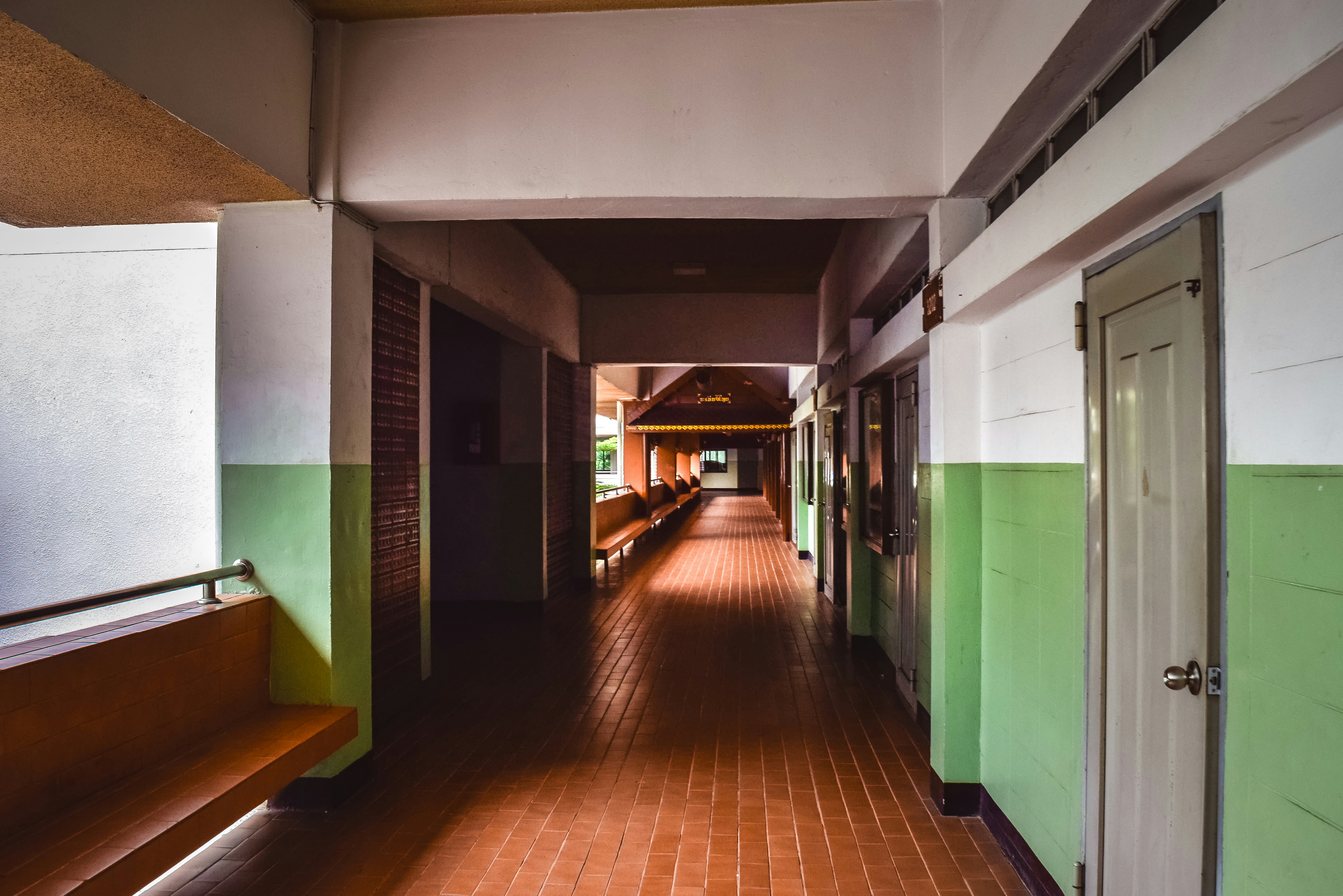 Rüyada eski okulunu görmeyi simgeleyen, nostaljik bir atmosferde güneş ışığı vuran boş bir okul koridoru ve sınıf görüntüsü.