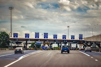 A blue truck driving down a highway under a cloudy sky
