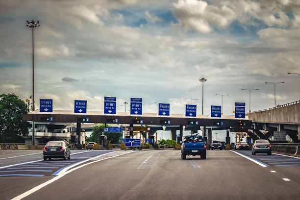 A blue truck driving down a highway under a cloudy sky
