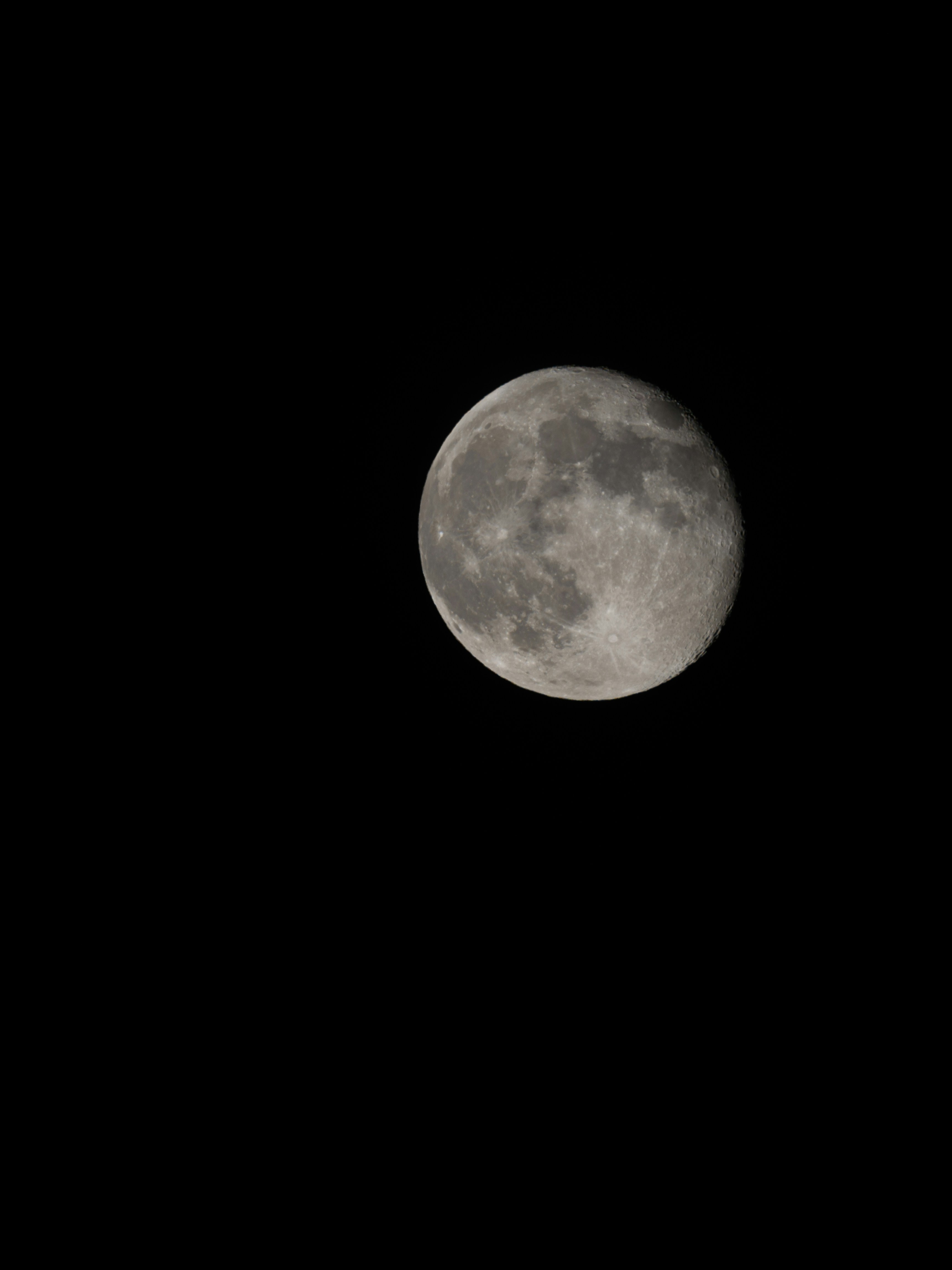 A full moon is seen in the dark sky