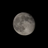 A full moon is seen in the dark sky