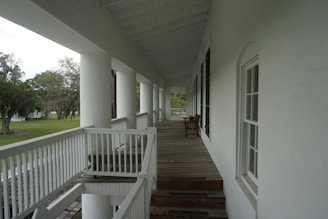 A long white porch with a set of stairs