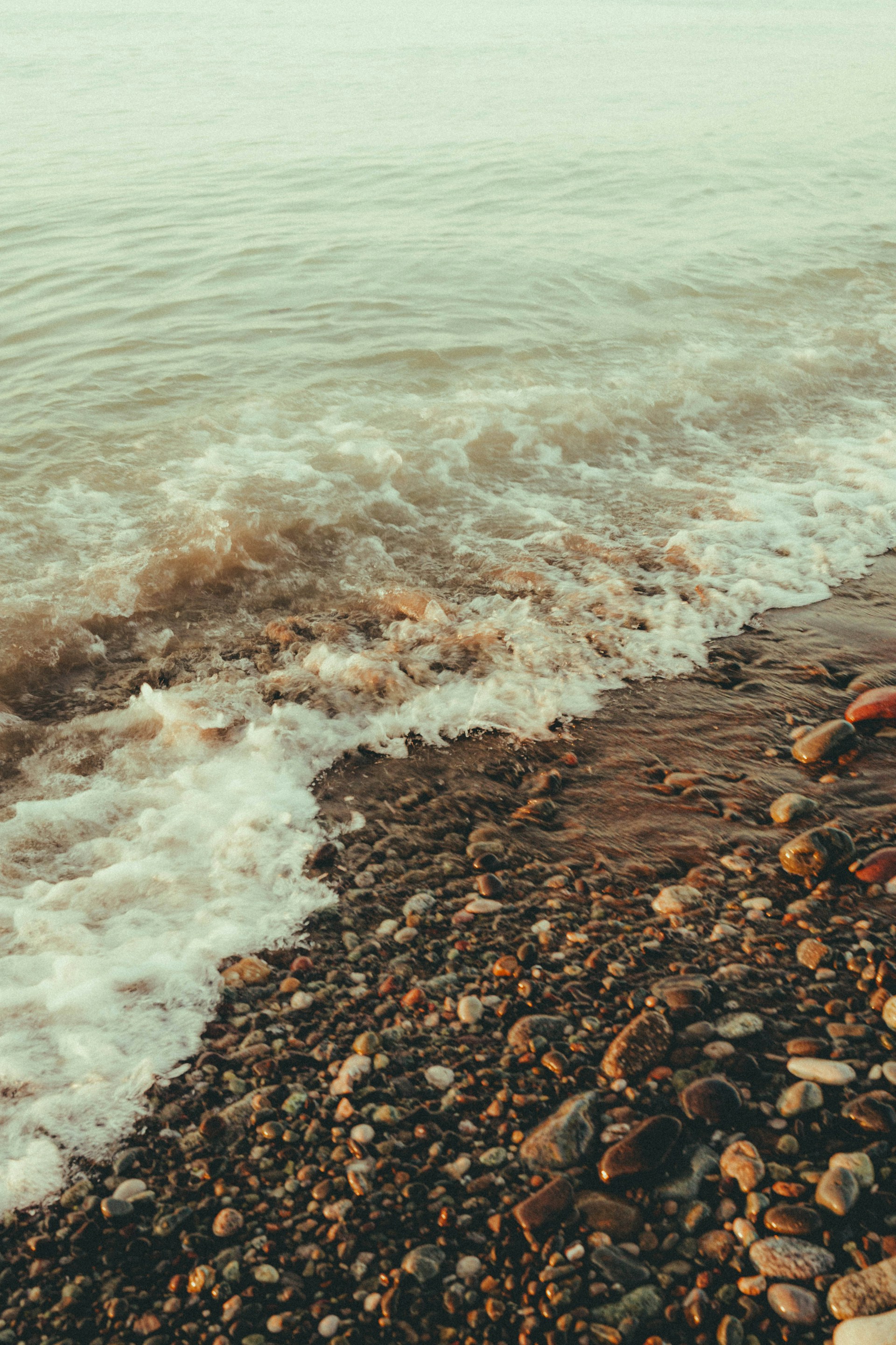 A person standing on a rocky beach next to the ocean