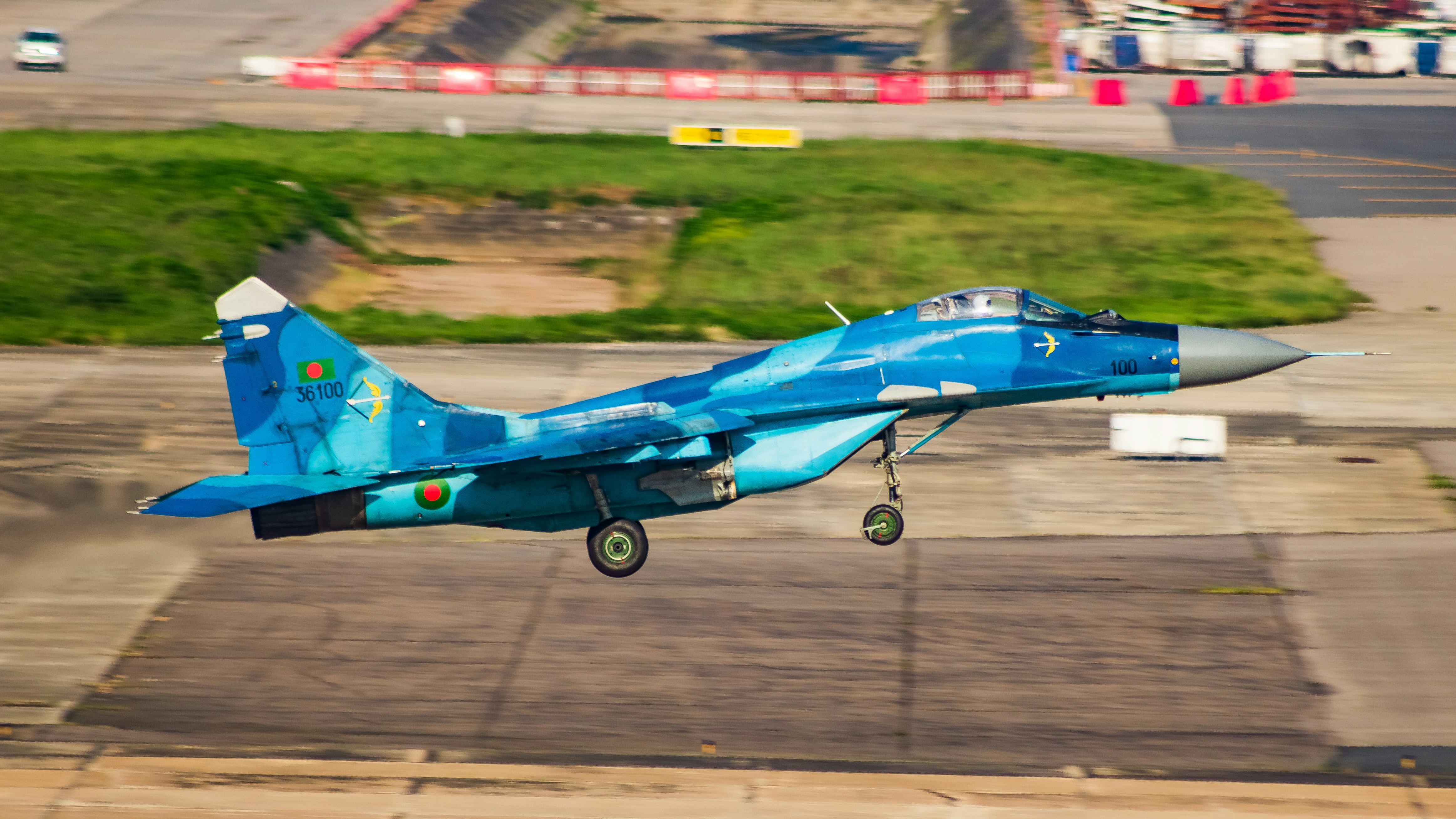 A blue fighter jet flying over a parking lot