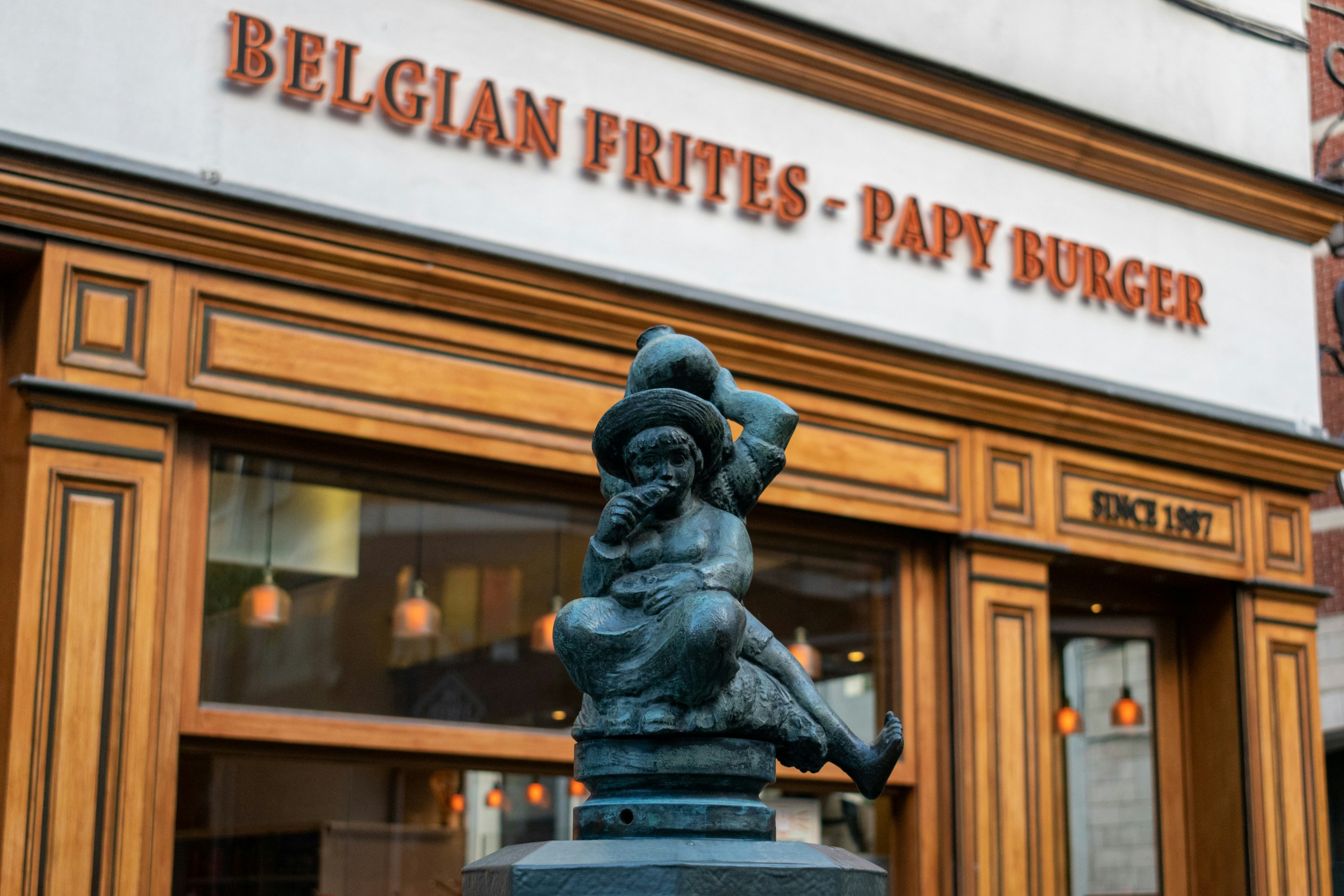 A statue of a person holding a hat in front of a building