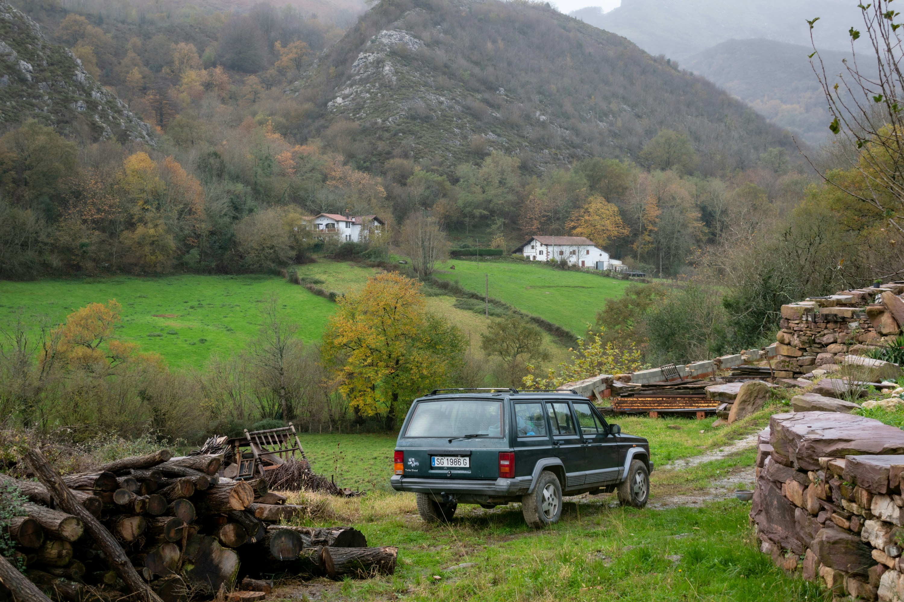 A car parked in front of a pile of wood
