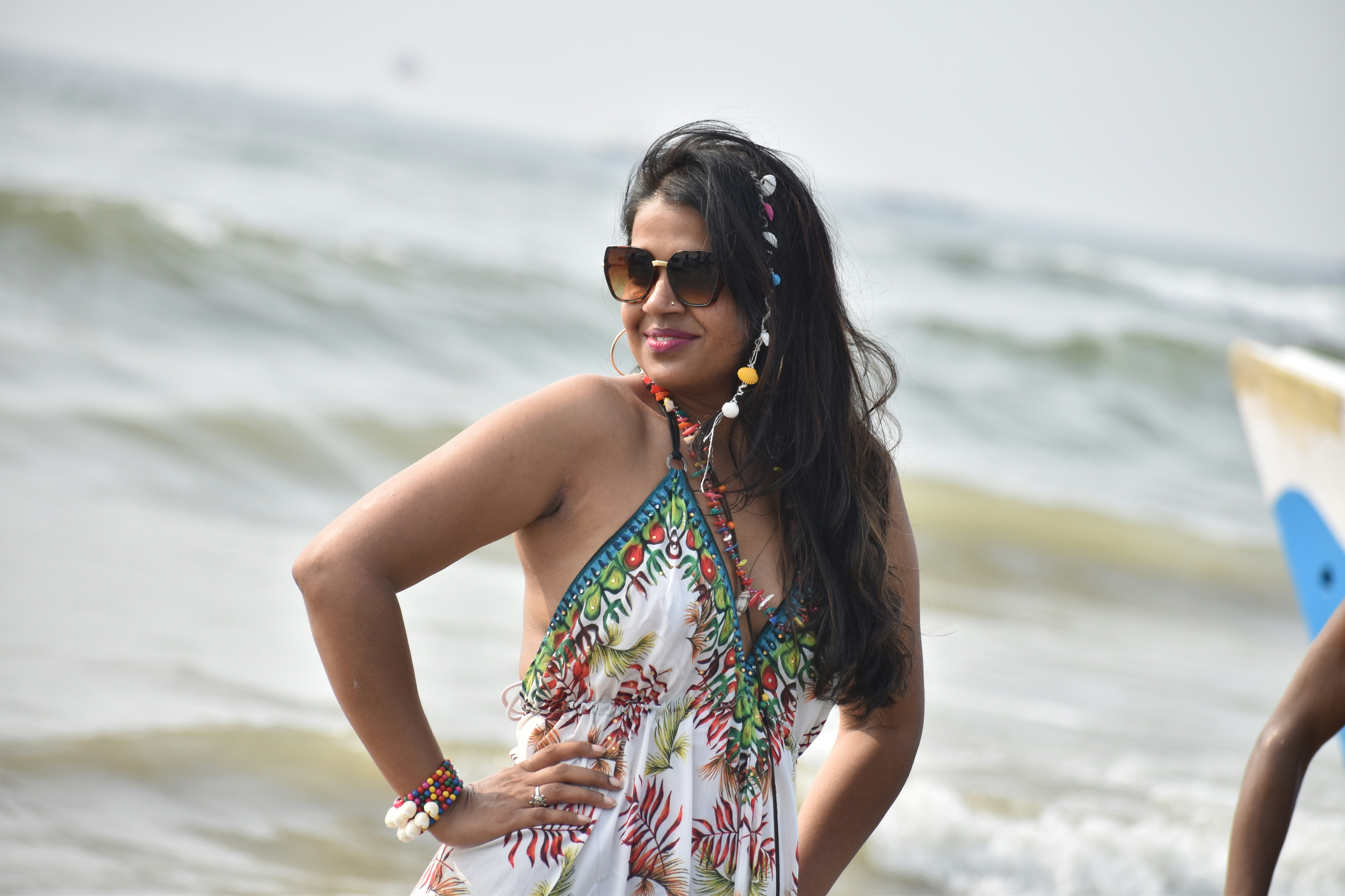 Woman in colorful summer dress on beach with ocean background