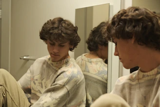 A young man sitting in front of a mirror
