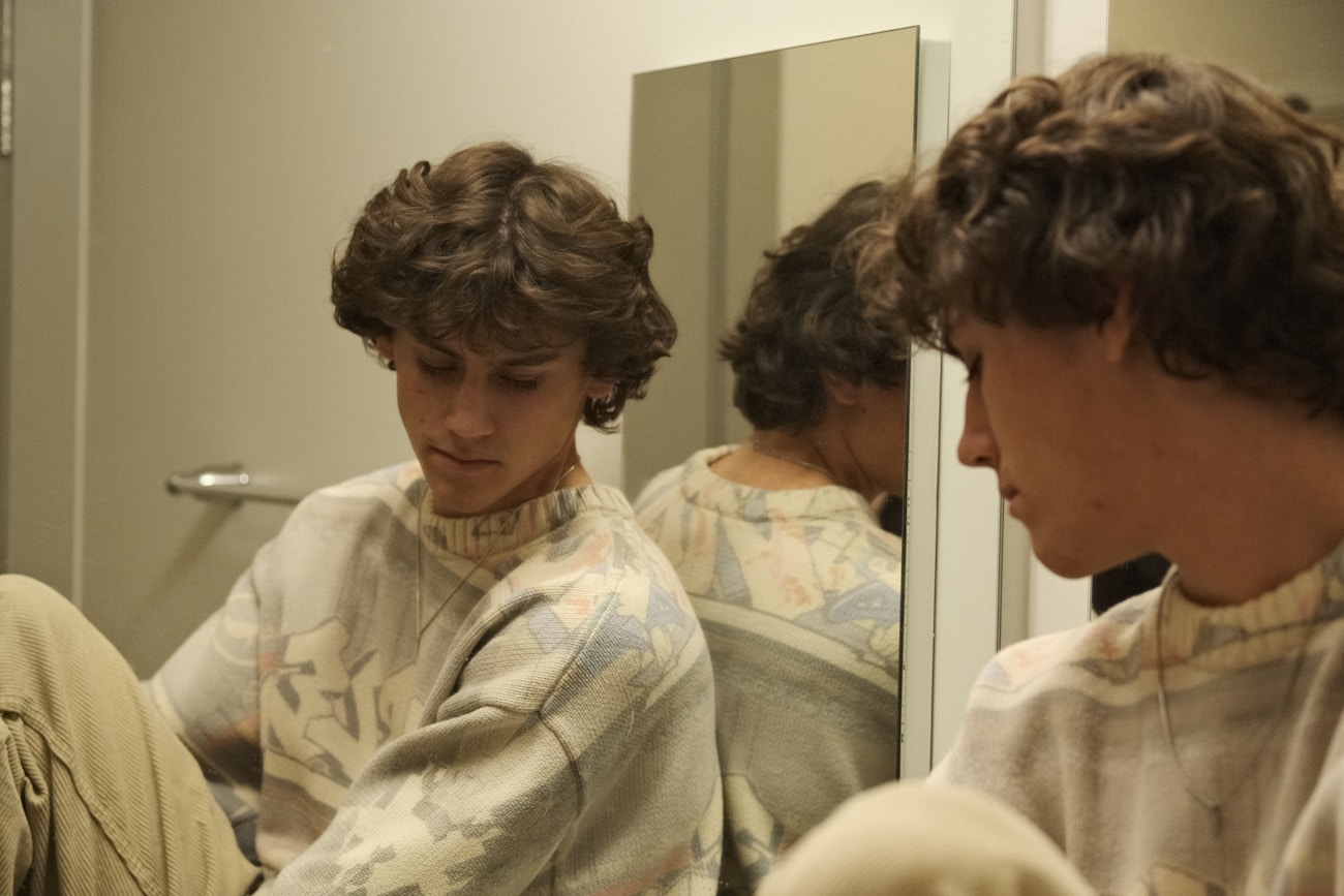 Young man sitting in front of a mirror for a creative portrait with reflections